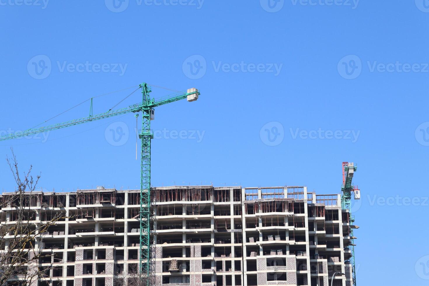 A modern construction site featuring cranes operating under a clear blue sky overhead photo