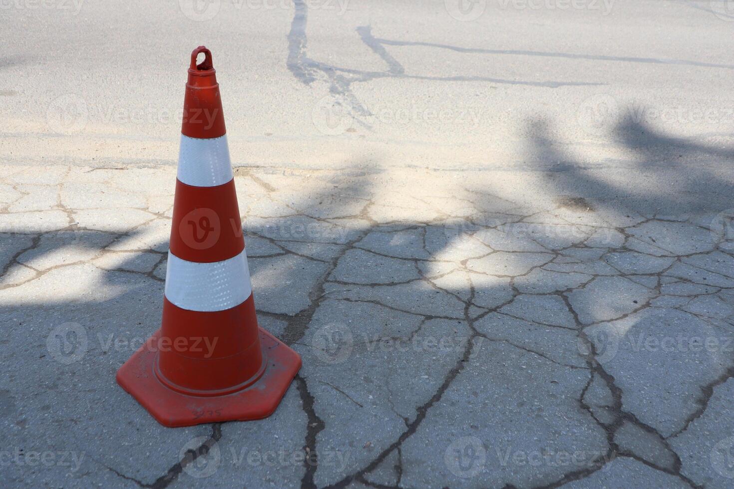 A traffic cone placed on a cracked pavement section captures attention and enhances safety photo
