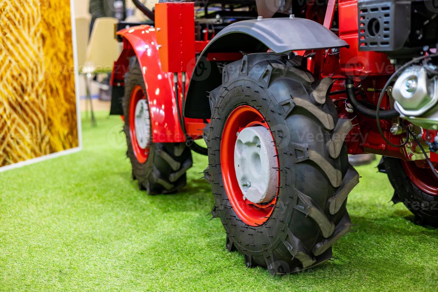 A red tractor with large tires on a green grass floor photo
