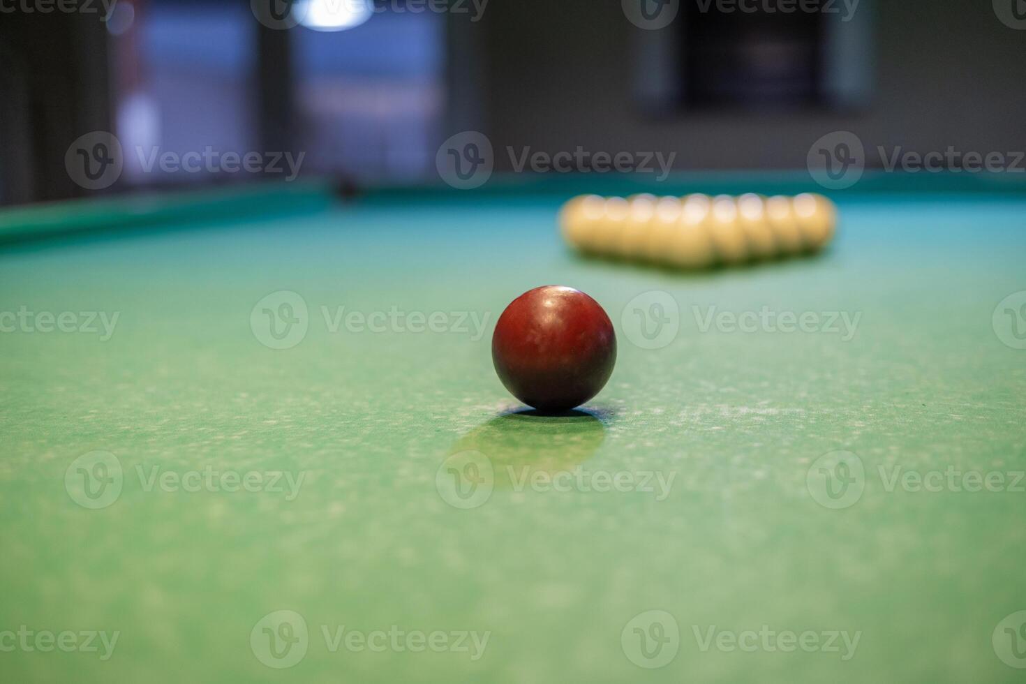 A red ball sits on a pool table photo