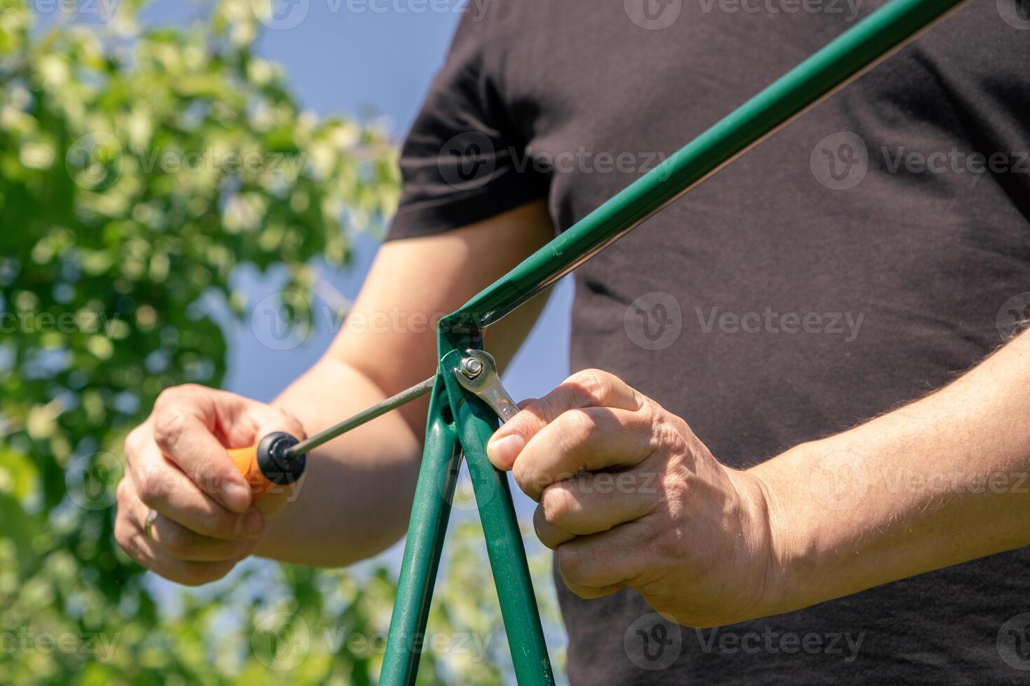 A man is using a tool to hold a green pole photo