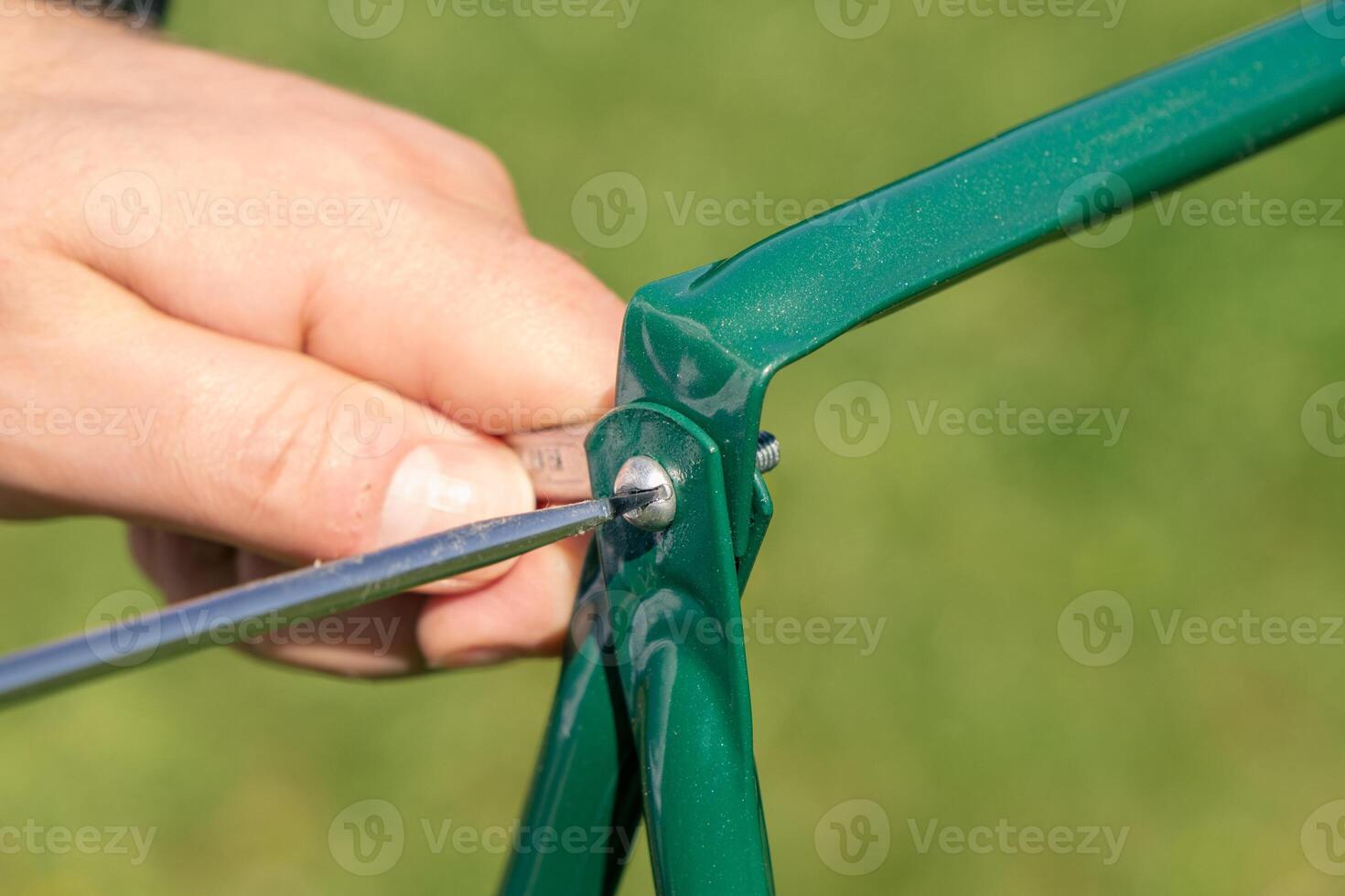 A person is holding a green metal tool to a green bicycle frame photo