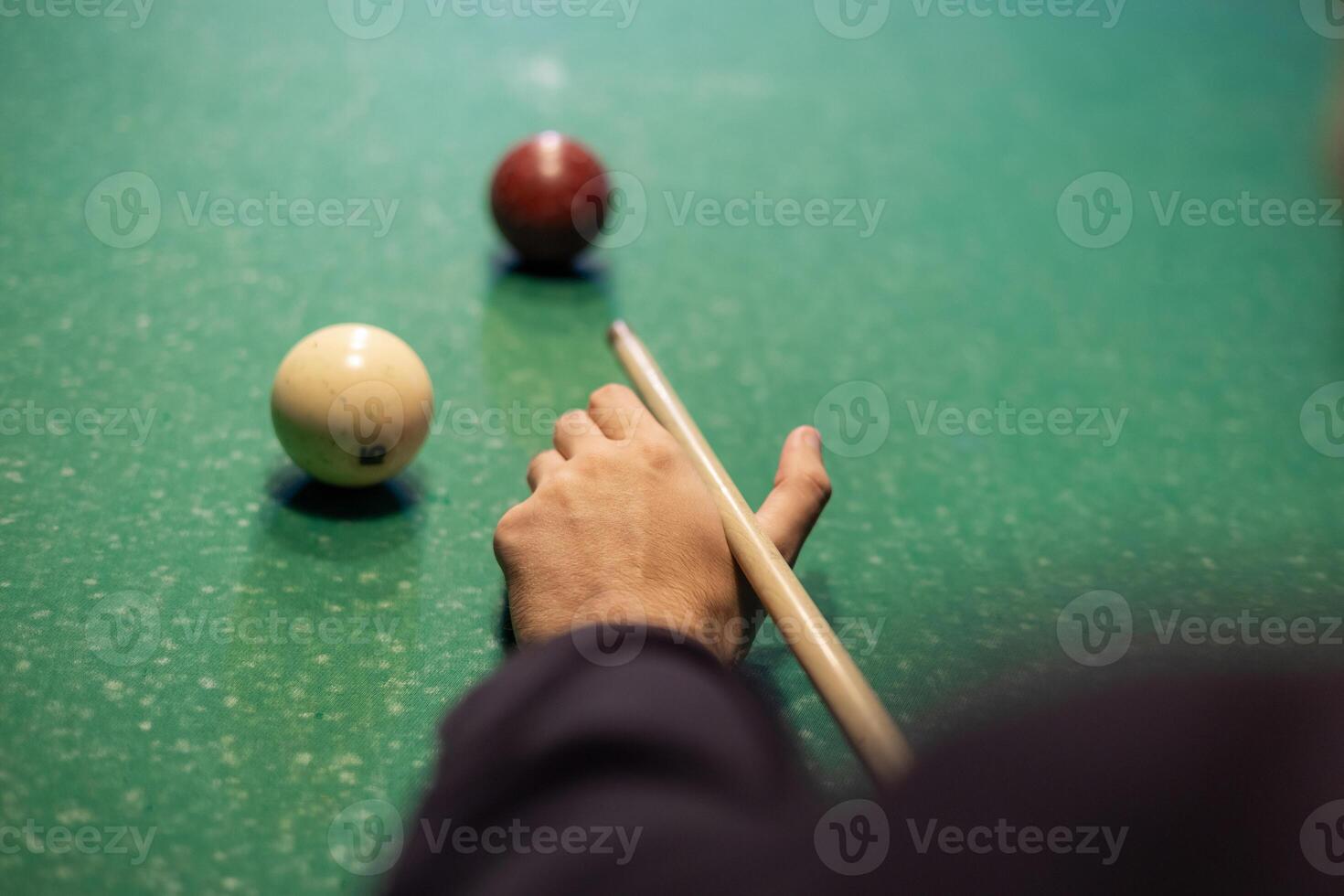 A person holding a cue stick and playing a game of pool photo