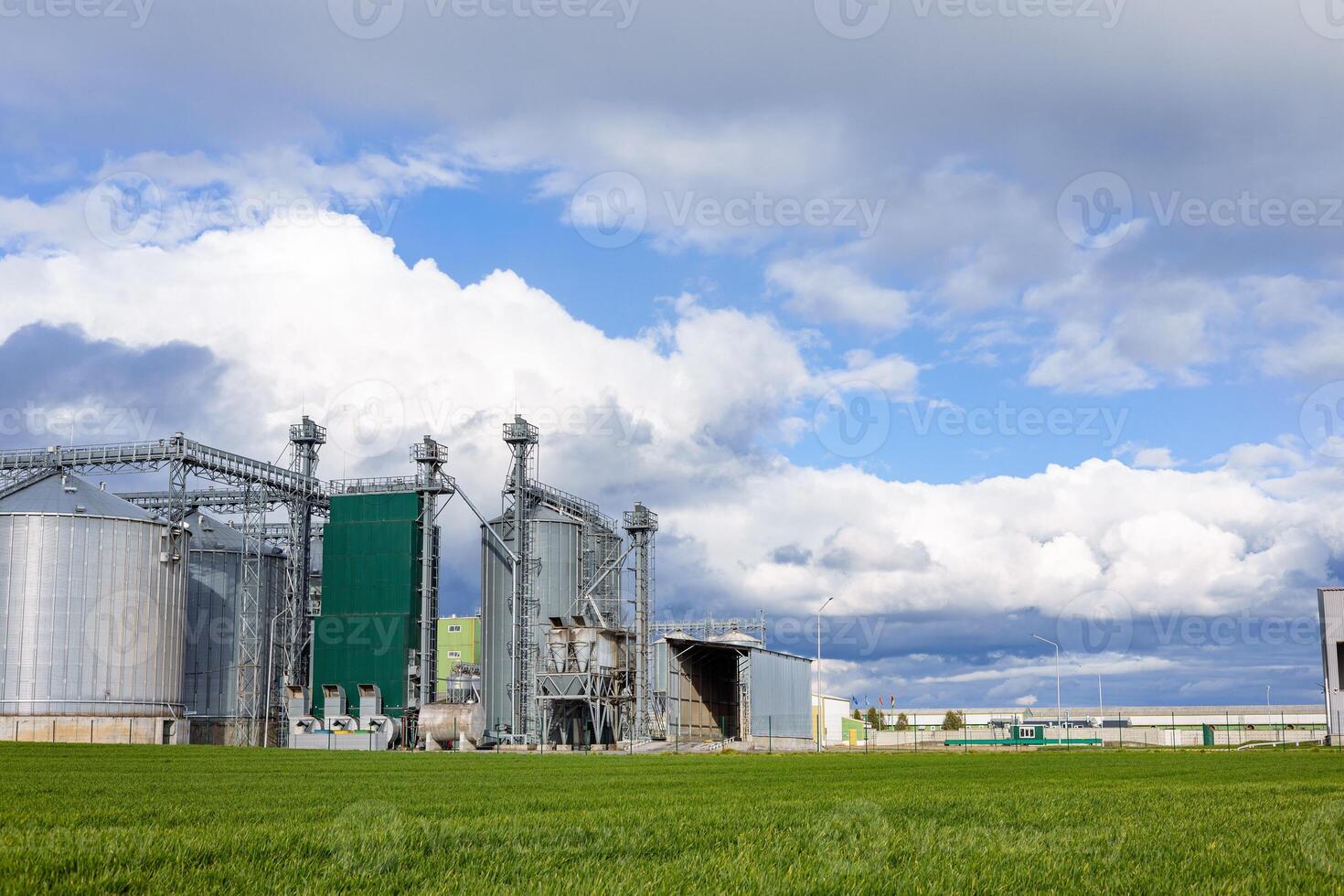 A large industrial building with green grass and clouds photo