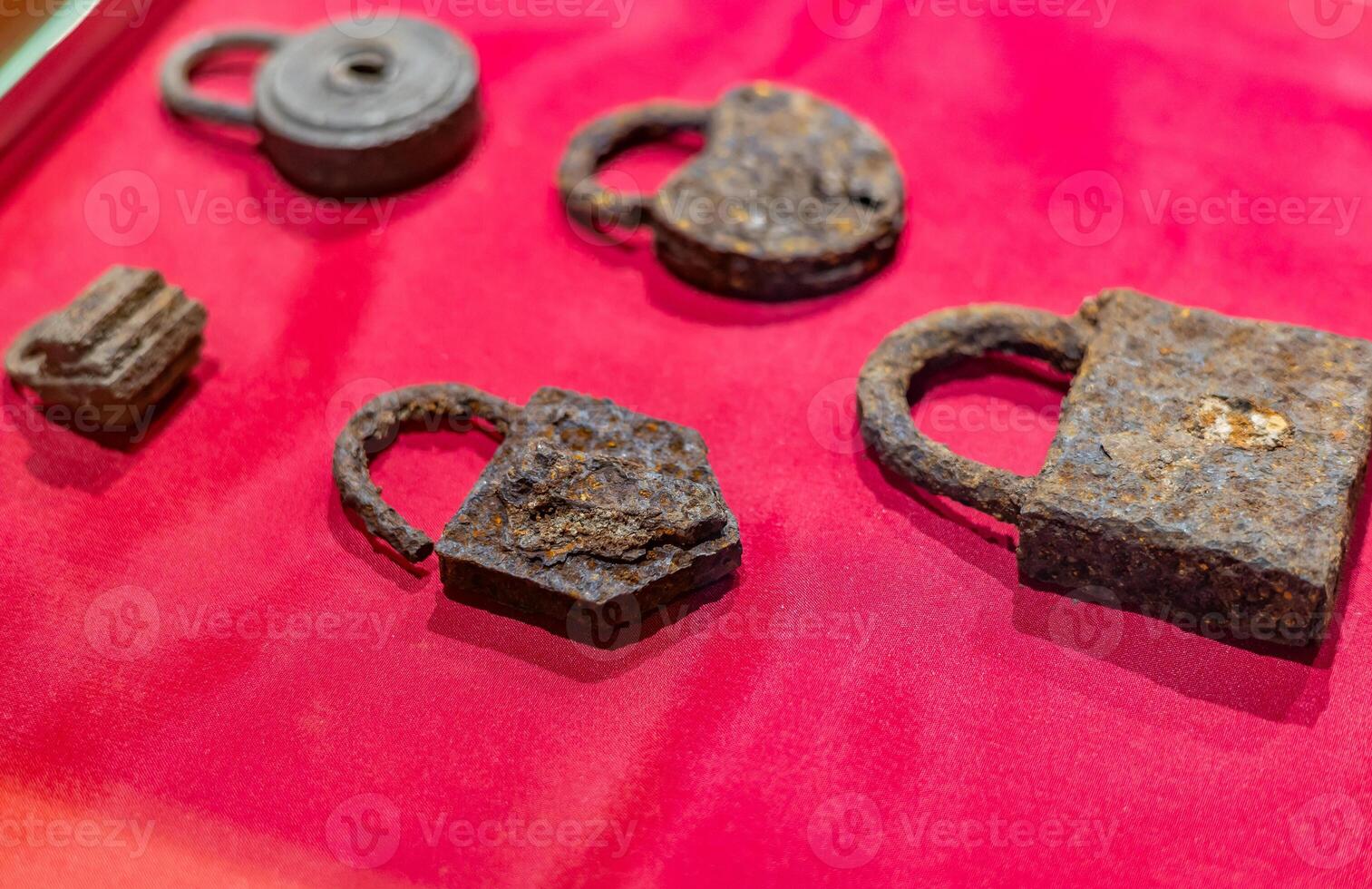 A display of old iron locks on a red cloth photo