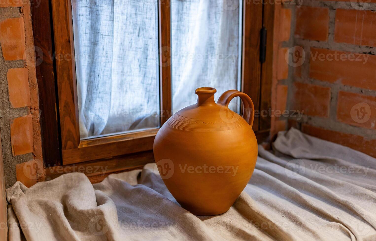 A brown vase sitting on a table near a window photo