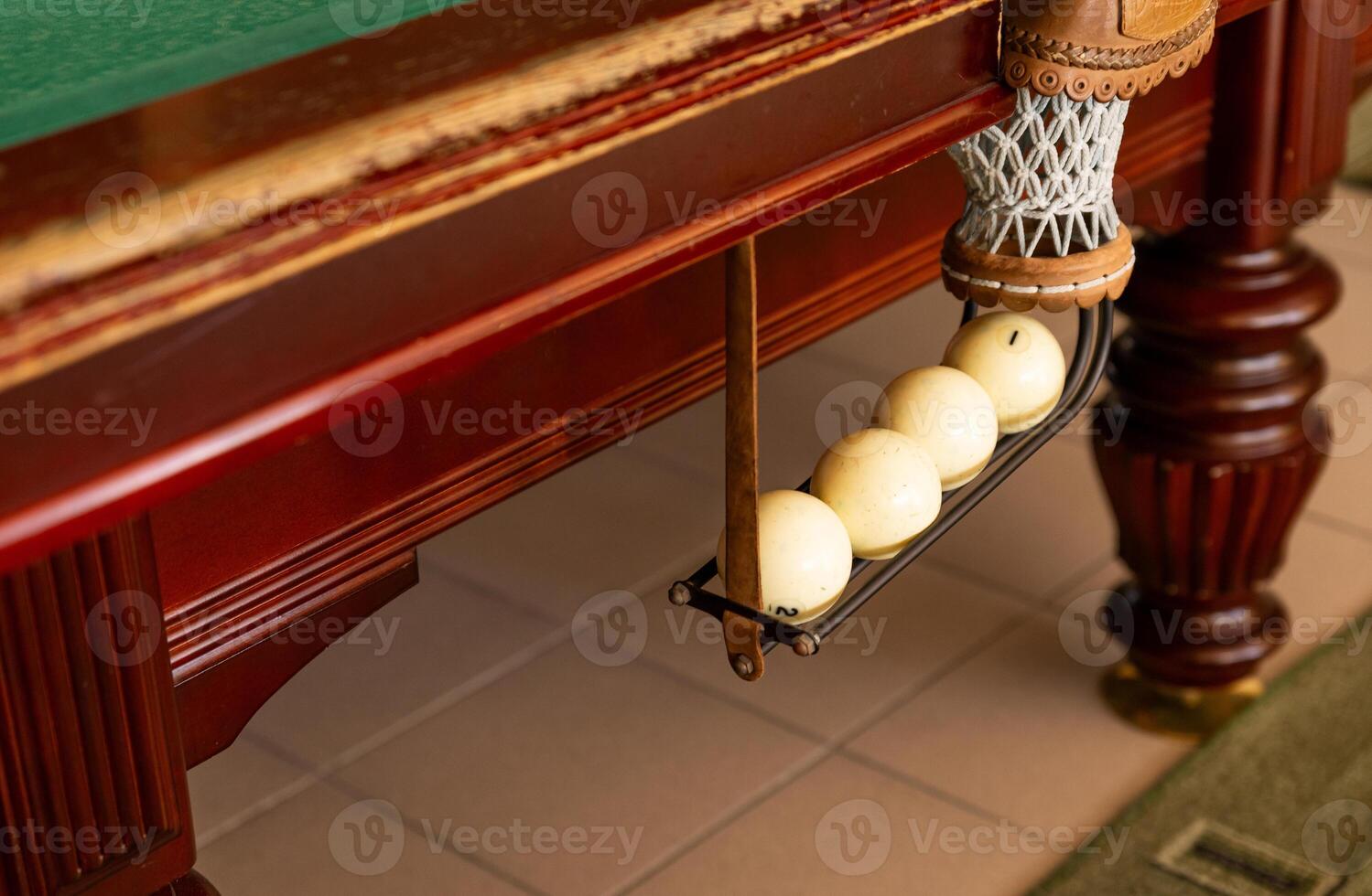 A collection of billiard balls that have entered the hole. There are colorful balls. The ball is under the billiard table. There are defects around the ball due to play photo