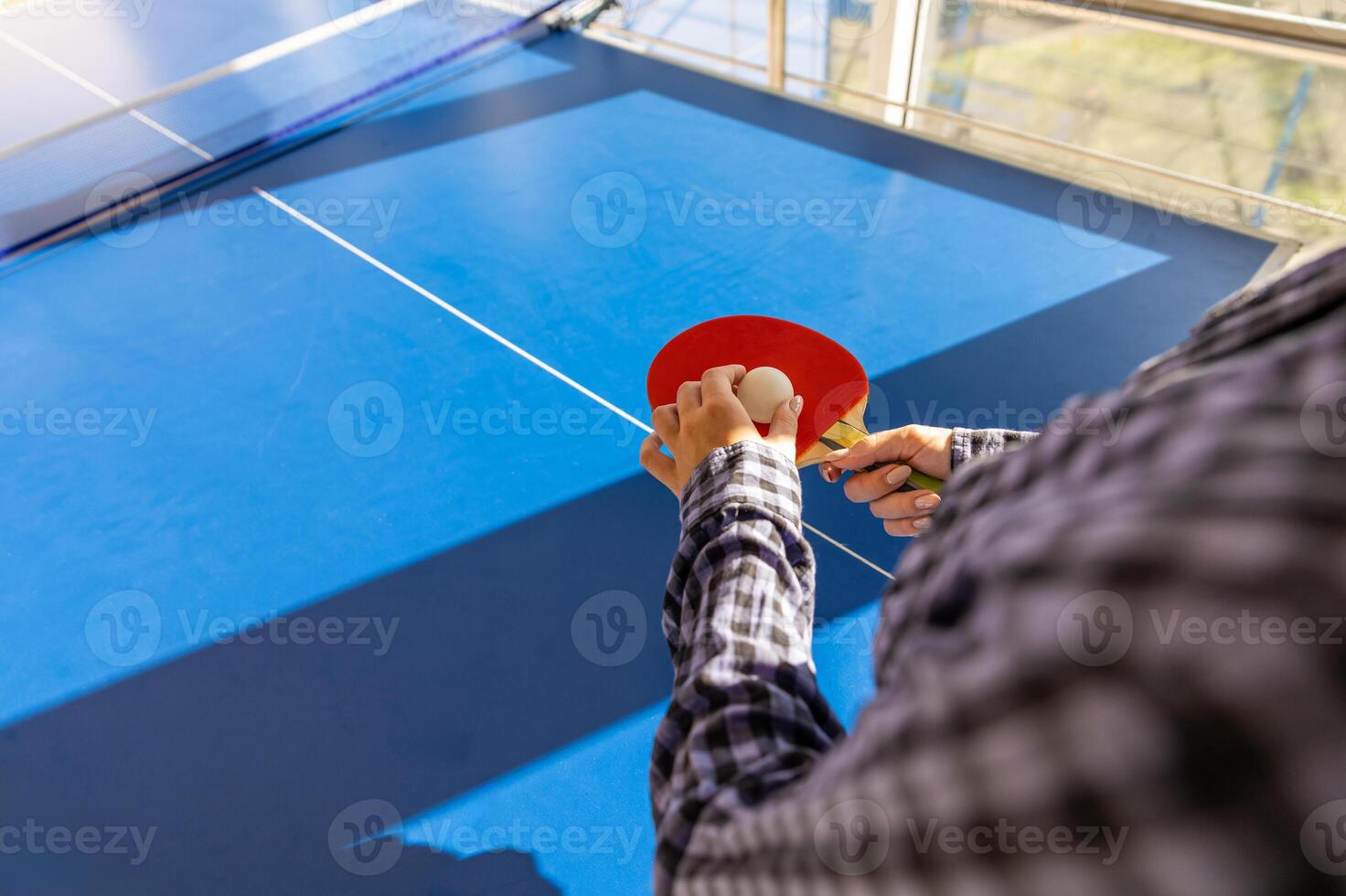 A person holding a ping pong paddle on a blue table photo