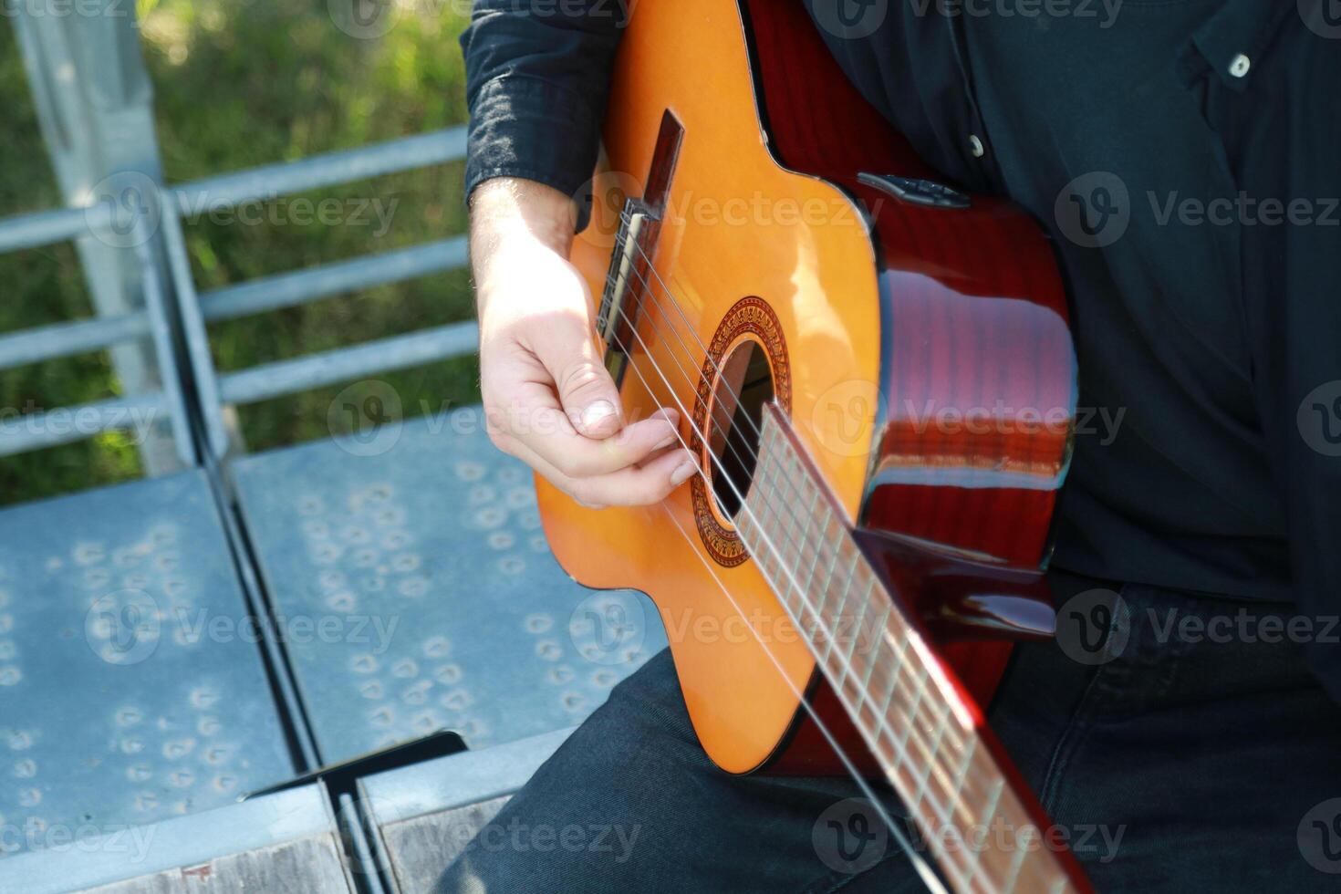 Man Tunes Guitar With Tuning Fork Outside Close up photo