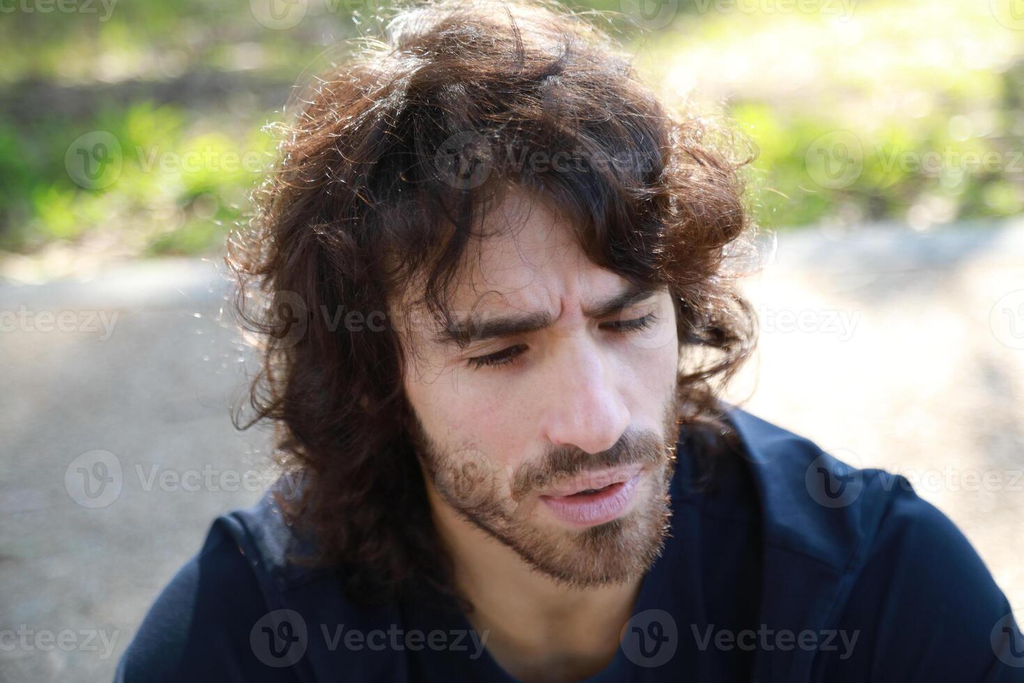 Pensive Long Hair Man Sitting On The Sidewalk Reflecting photo