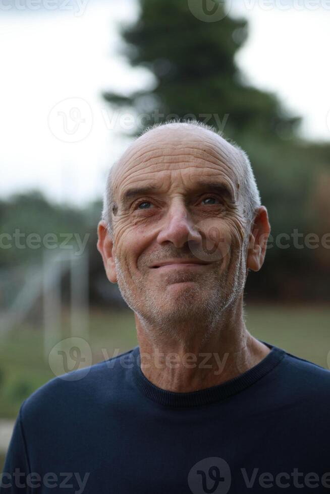 Bald Senior Man Smiles Facial Expression In The Nature Among The Trees Vertical photo