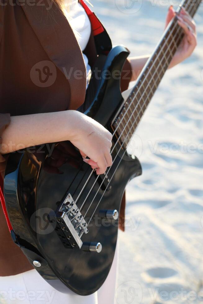 Girl Plays Bass Music Instrument On The Beach At Sunset Near Ocean Vertical photo