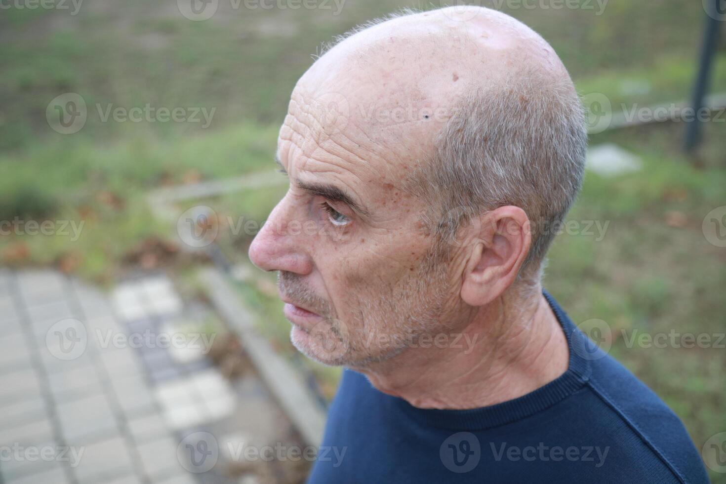 Bald Senior Man In Nature Park Looks In Shock Near Trees Outdoor close up photo