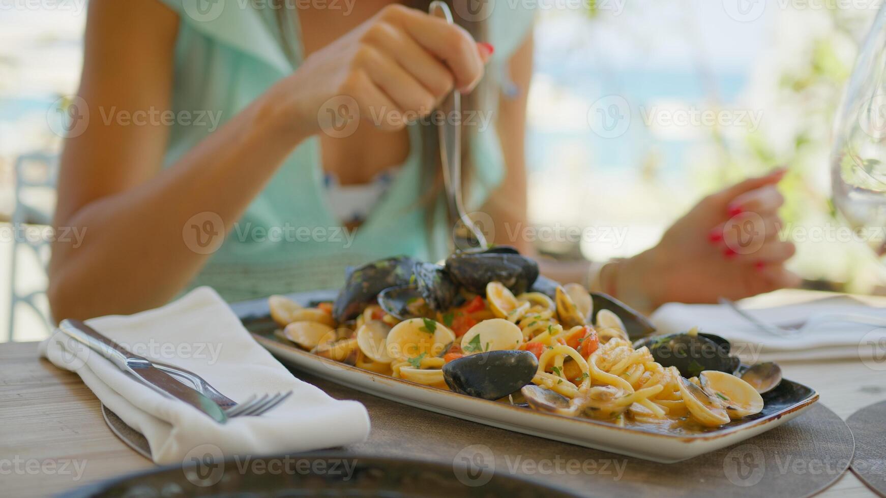 Woman Savoring The Gourmet Seafood Spaghetti Dish At The Beach Resort Near Sea photo