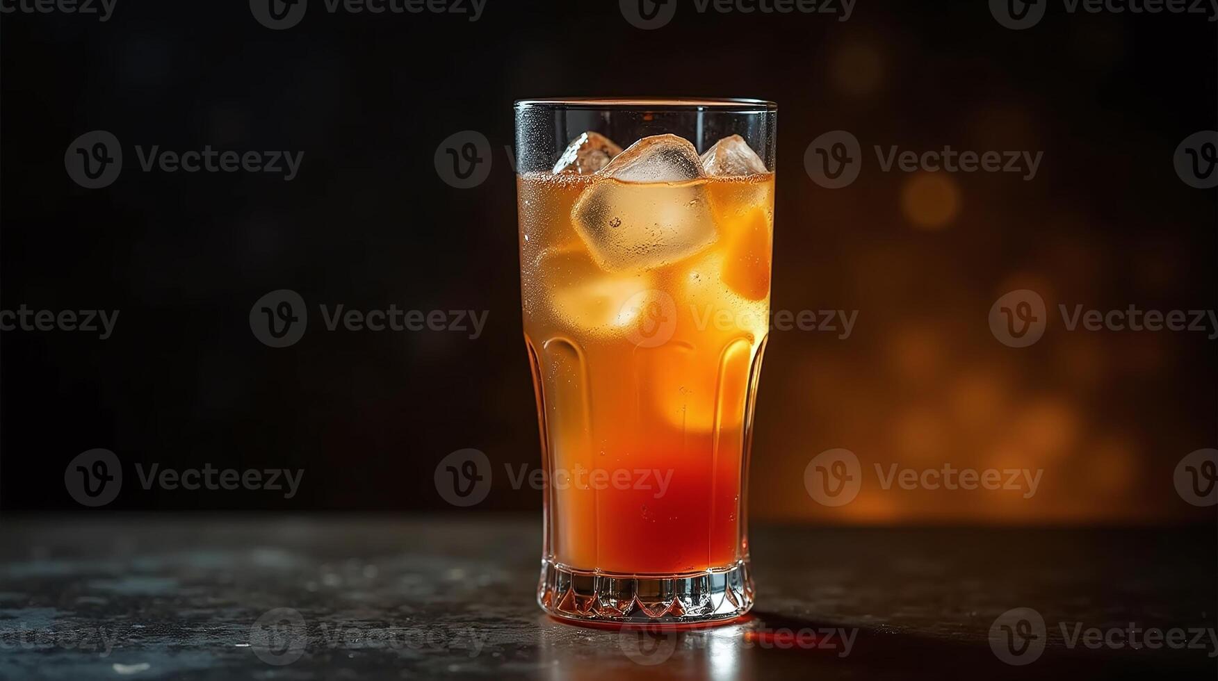 Amber-colored beverage with ice cubes in a clear glass on a dark surface. photo