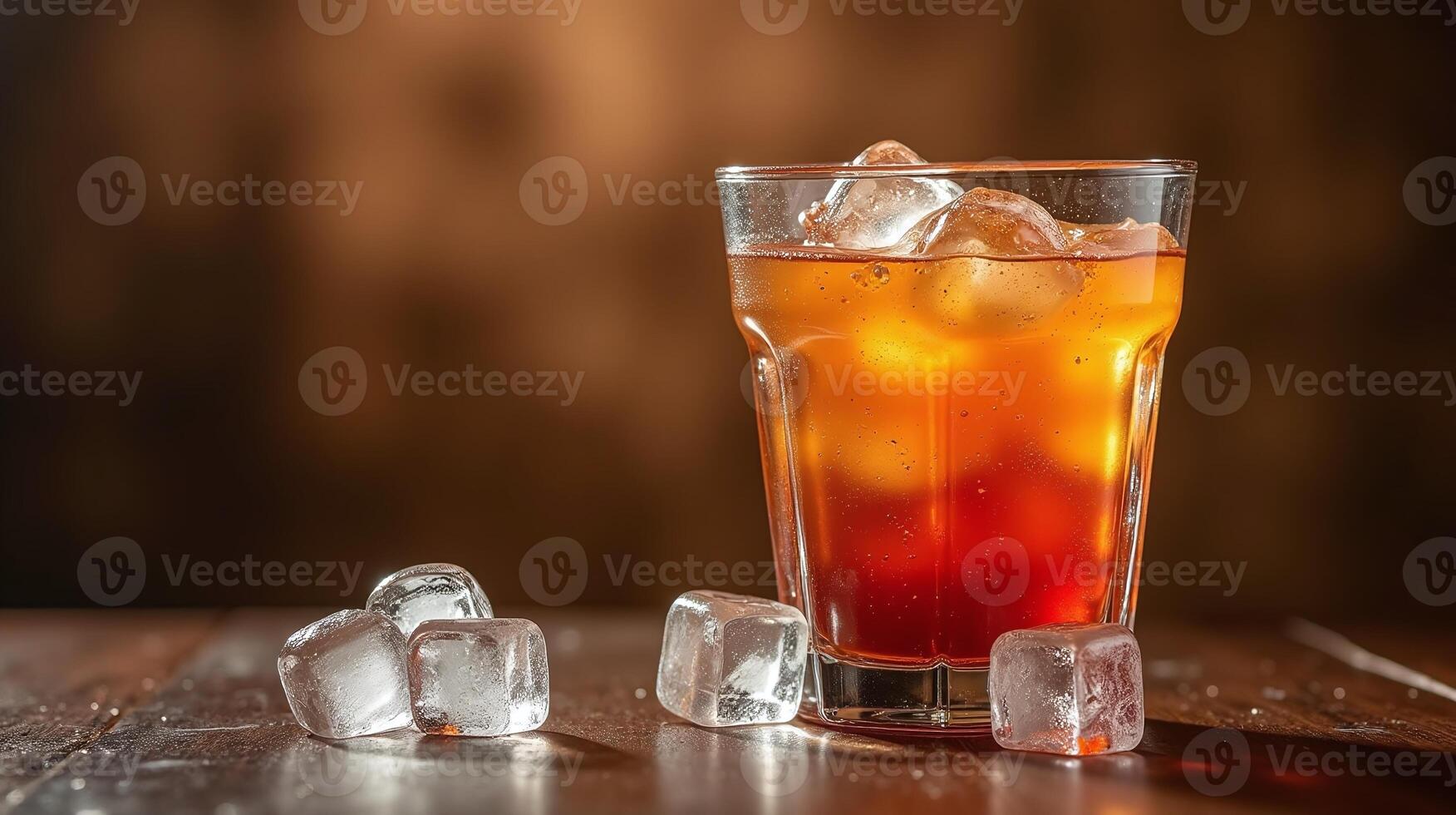 A glass of amber-colored beverage with ice cubes on a dark wooden surface, set against a blurred warm background. photo