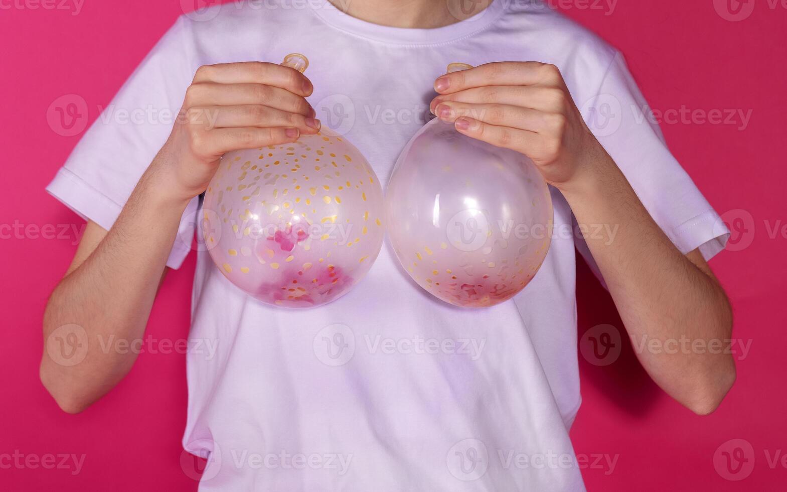 Close-up of a woman hands holding two inflated balloons near her chest. The concept of breast augmentation and lifting. photo