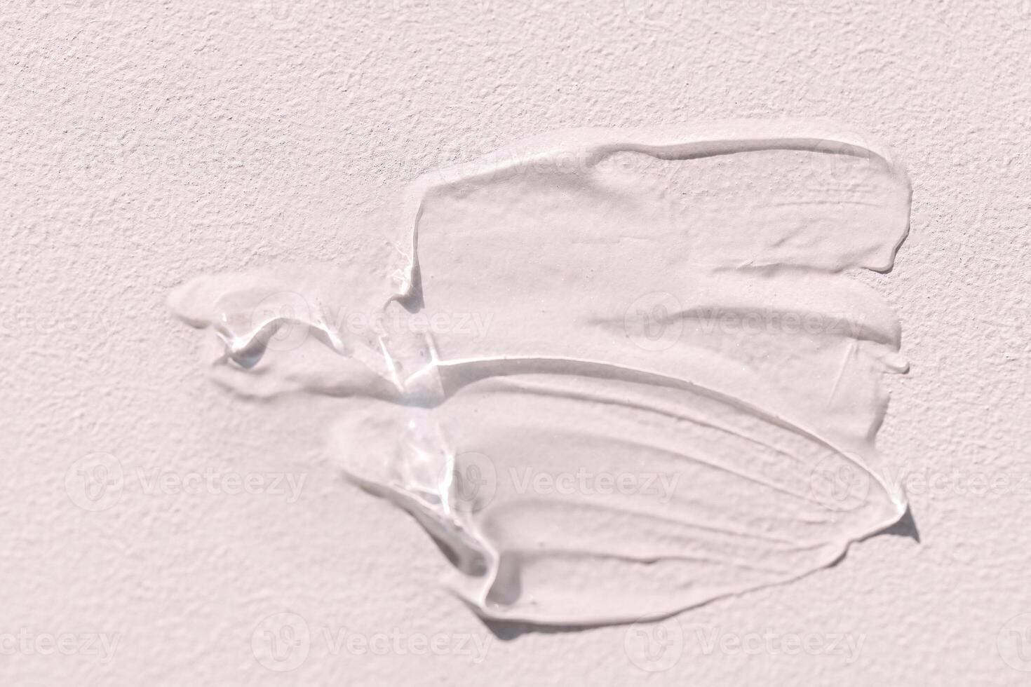 The texture of the cream on a light background. Translucent serum is smeared on the backdrop. The consistency of glycerin gel. Cosmetic smear. photo