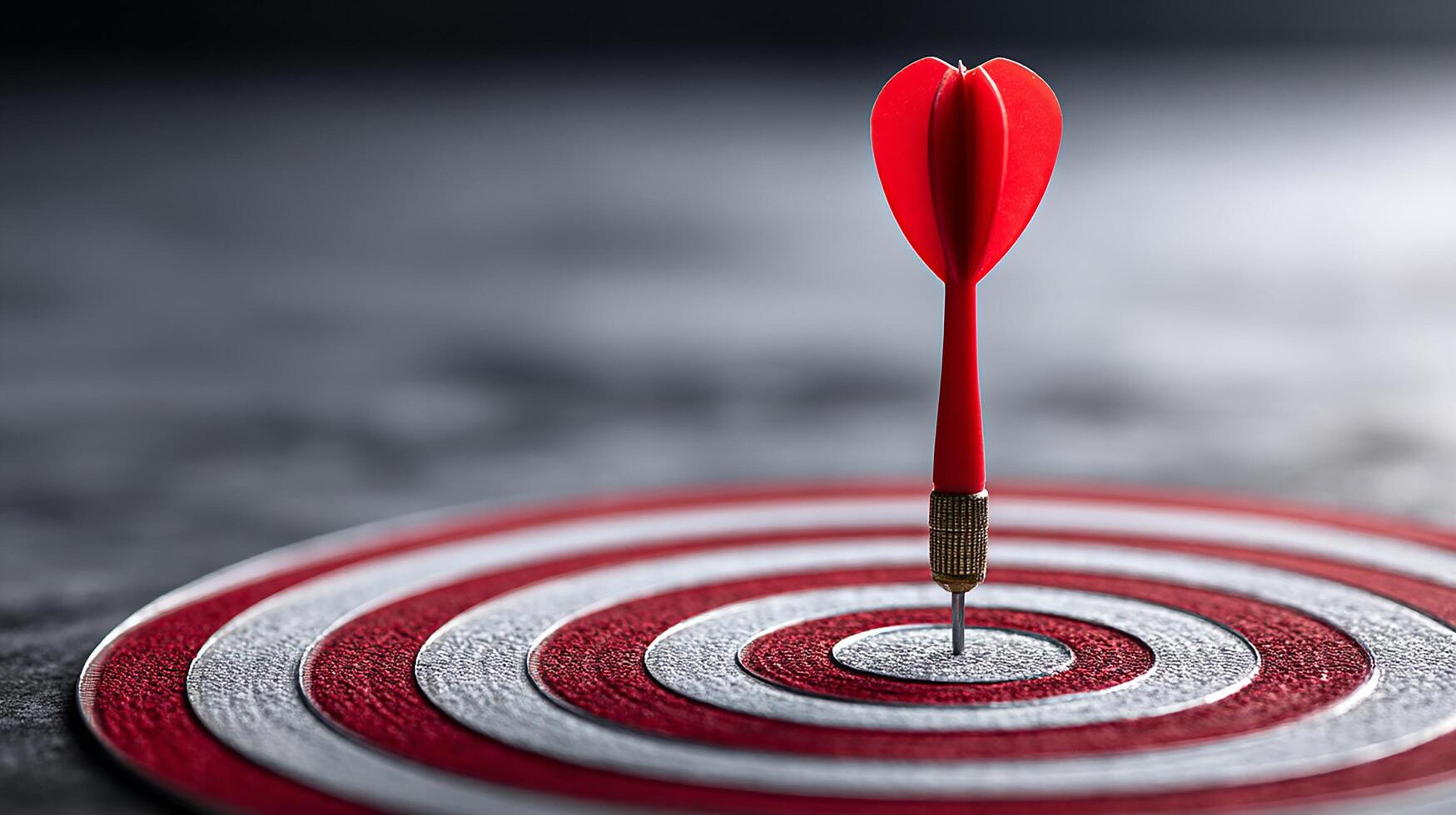 A red dart is perfectly placed at the center of a bullseye target. photo