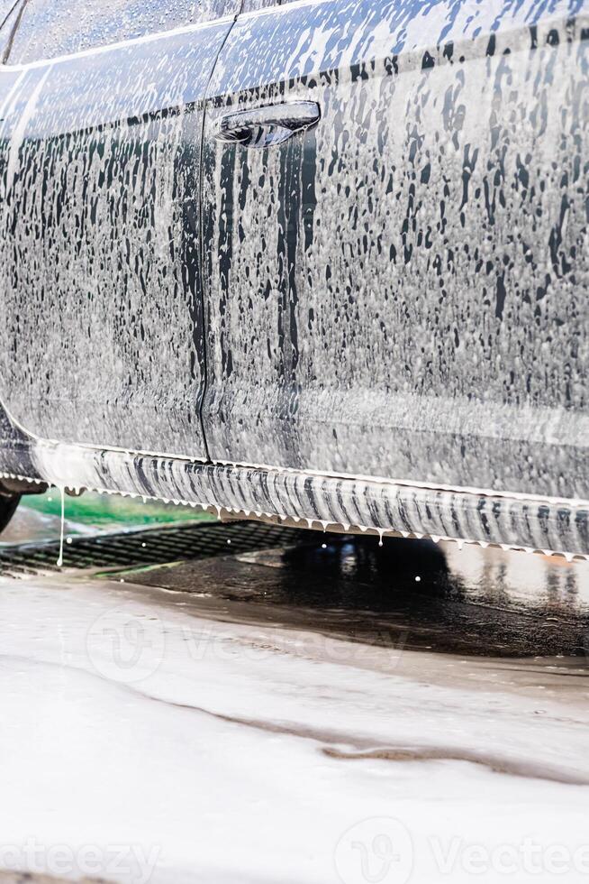 Car washing process showing foam and water dripping at a vehicle detailing location photo
