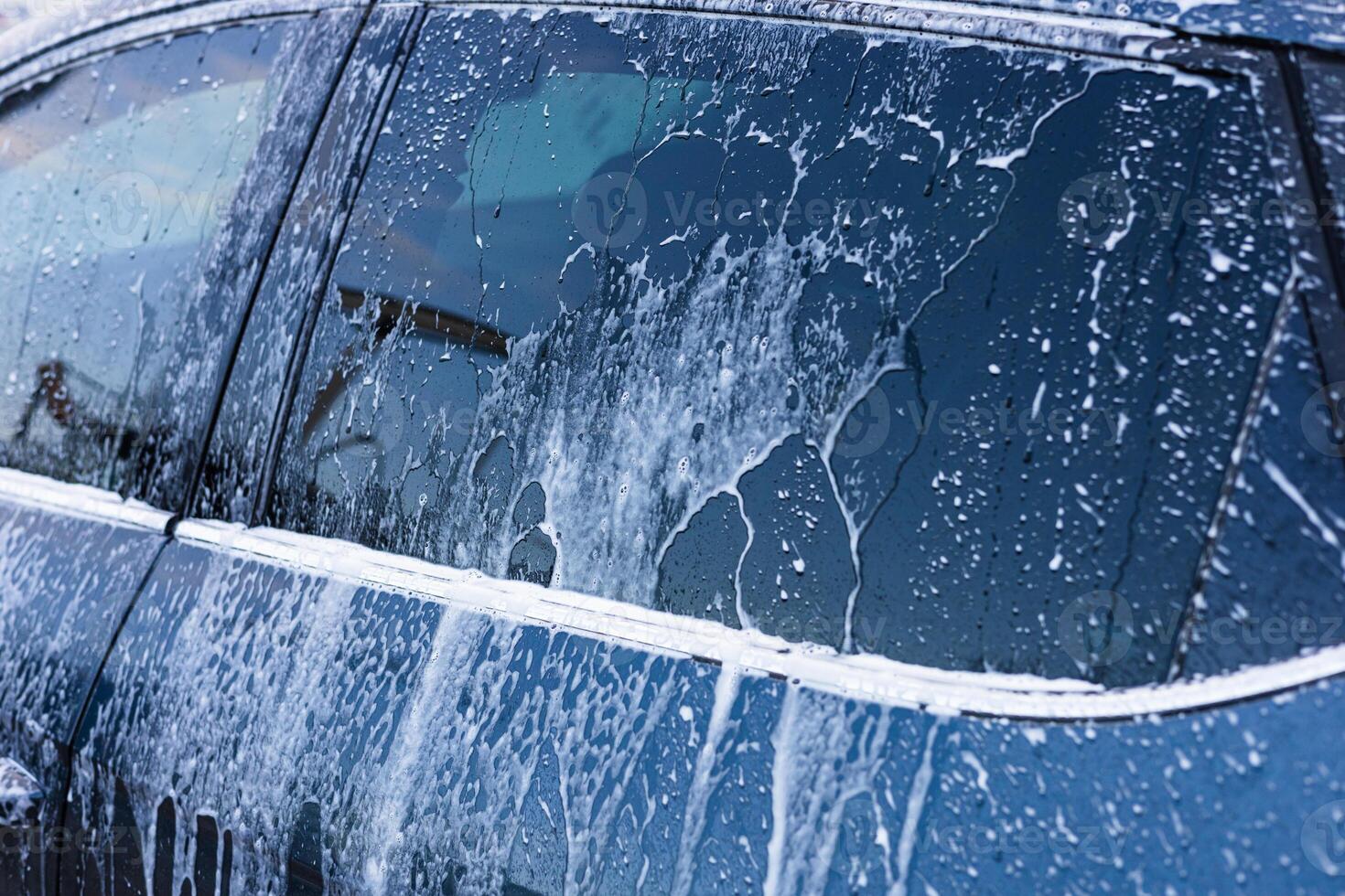 Bubbles and suds cover a car during an exterior wash on a sunny day at a local car wash photo