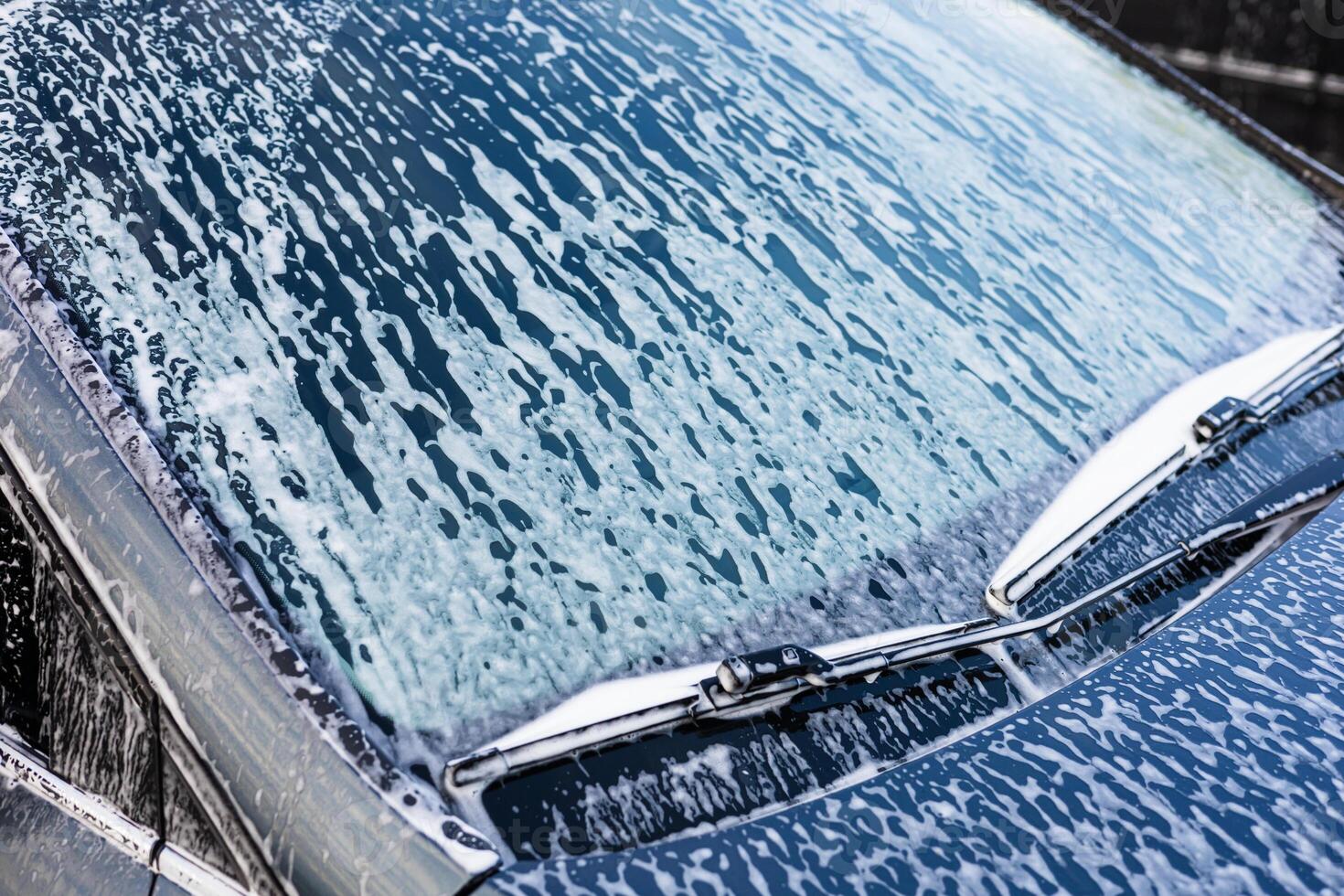 Washing a car with soap on a sunny day in a driveway near the home photo
