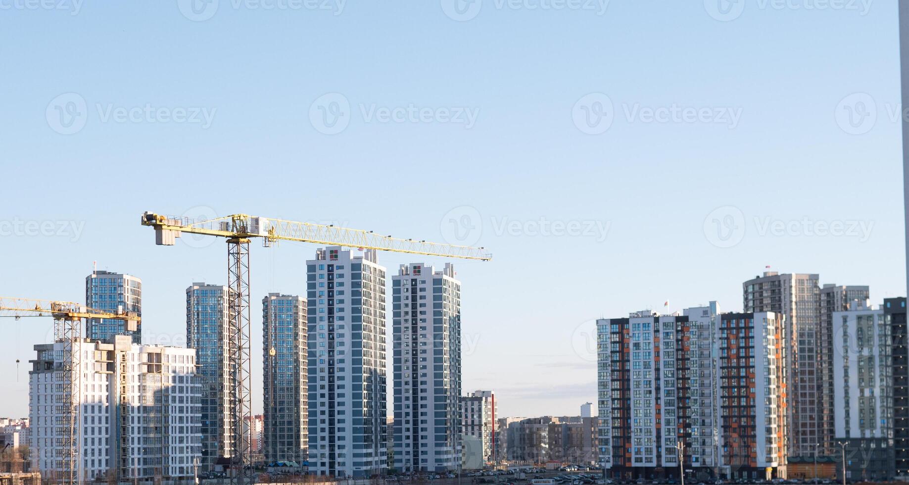 A panoramic view of urban construction with cranes and tall highrises set against a bright blue sky photo