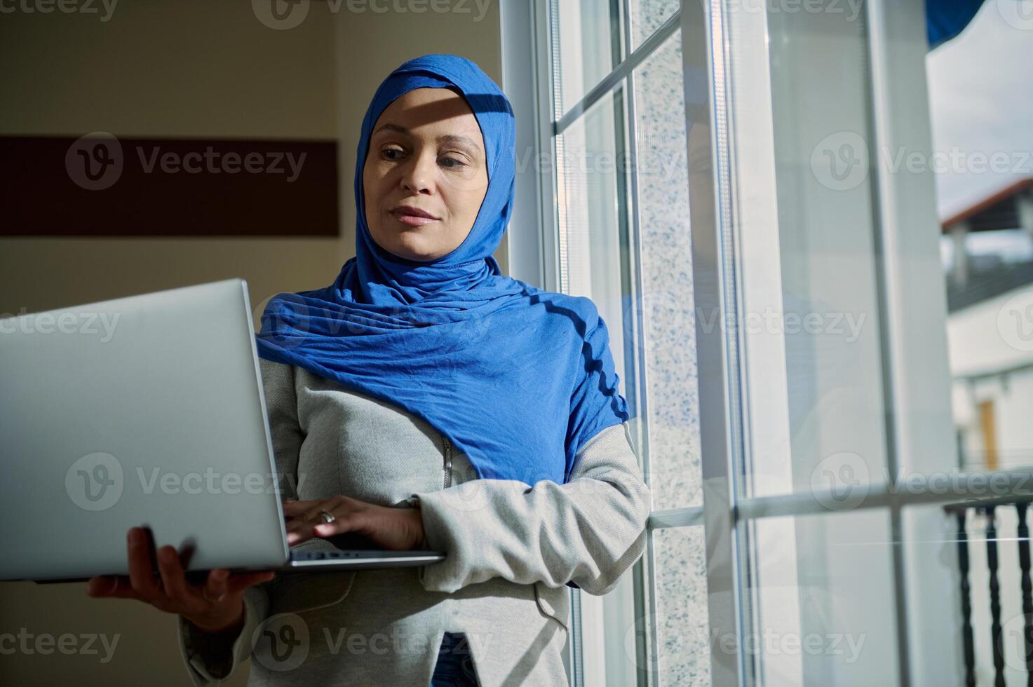 Professional Woman Using Laptop in Modern Work Environment by Window photo