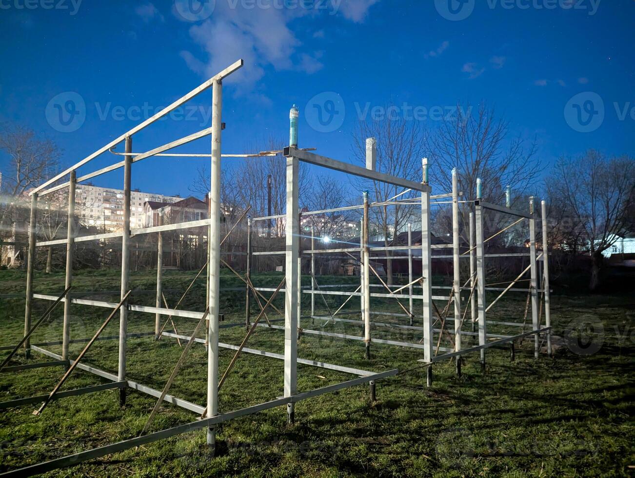 A metal structure sits in a grassy field at night photo