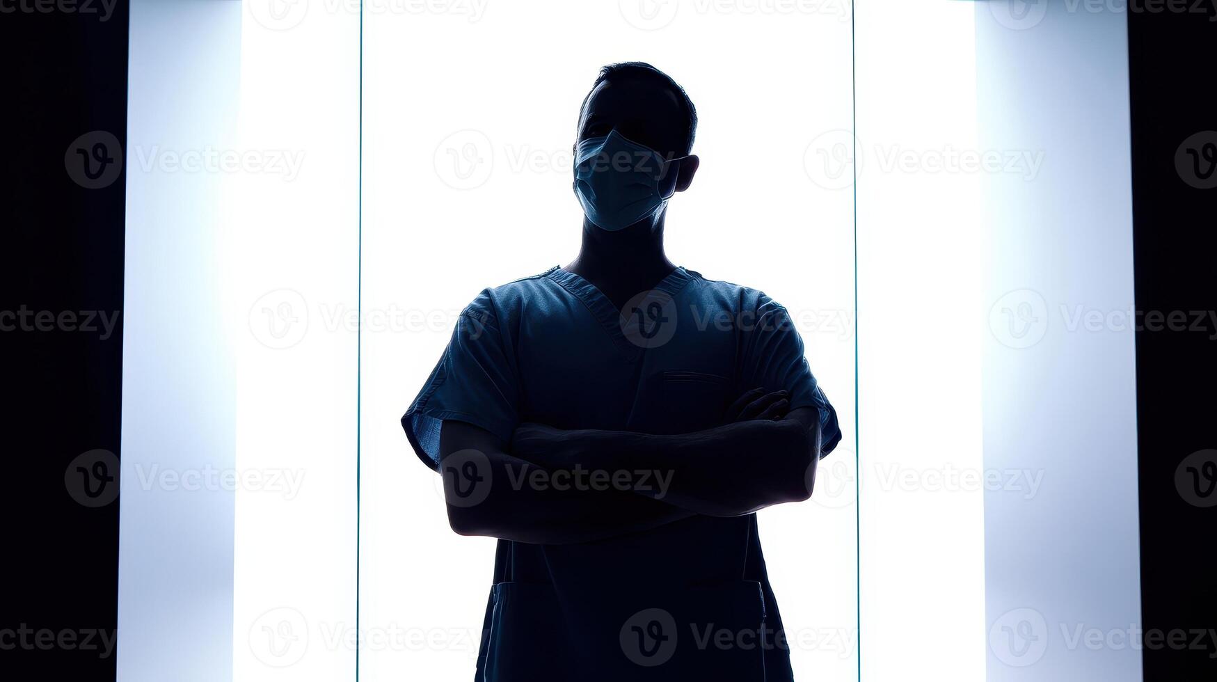 Silhouette of a surgeon in scrubs with arms crossed in a bright setting photo