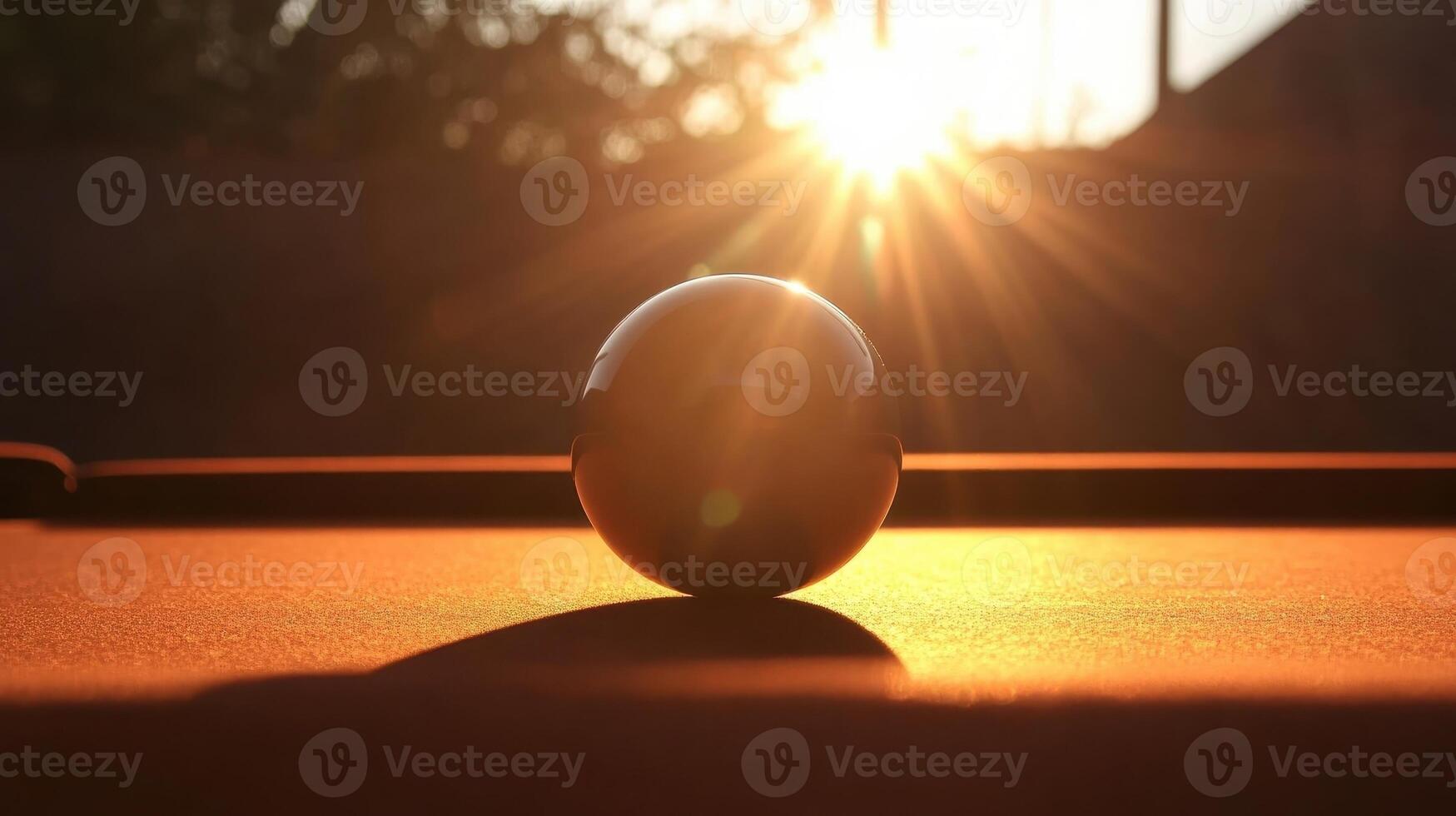 Dynamic silhouette of a pool ball with sunset glow over a billiard table in a serene setting photo