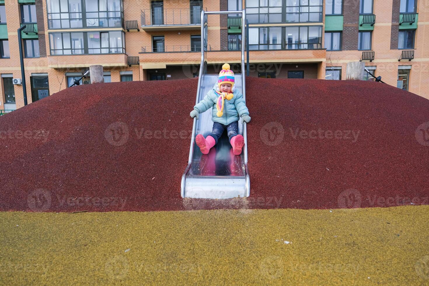 A young child is sliding down a slide at a playground photo