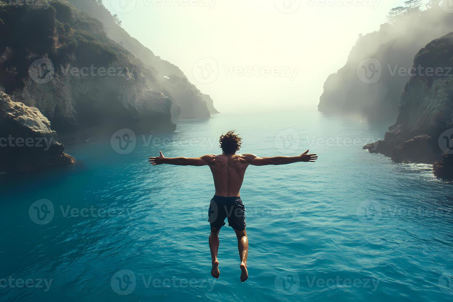 Man diving into ocean between cliffs with open arms photo