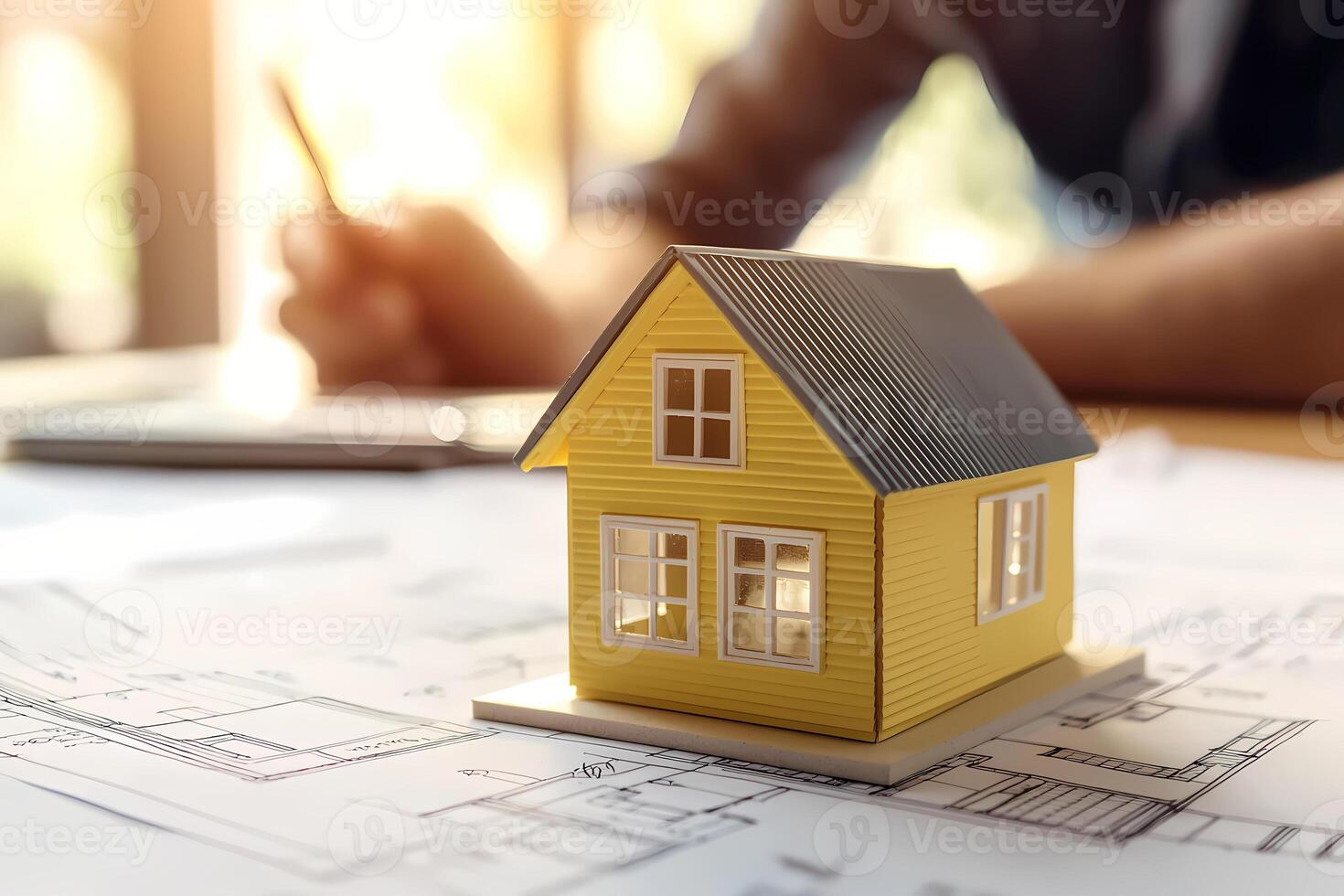 Architect designing residential building using blueprint and miniature house photo
