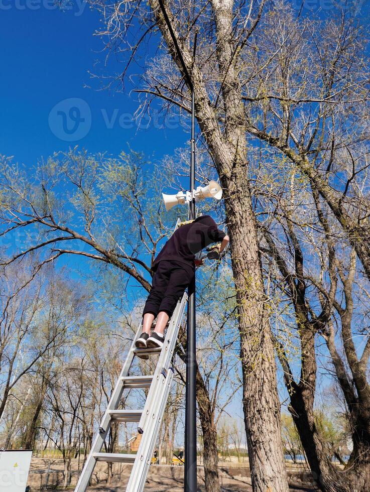 Worker installing security cameras and megaphone on lamp post photo