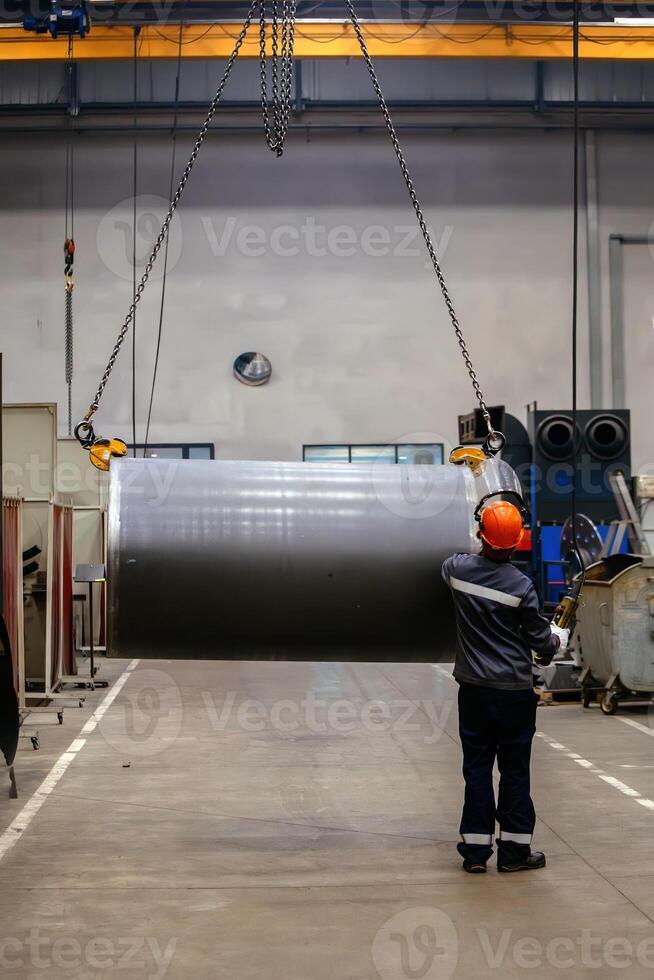 Pipe on overhead crane. Worker with remote control photo