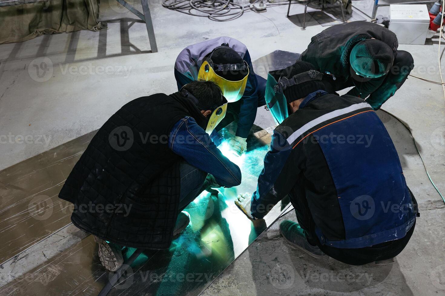 Group of factory workers in protective mask welding iron parts. photo