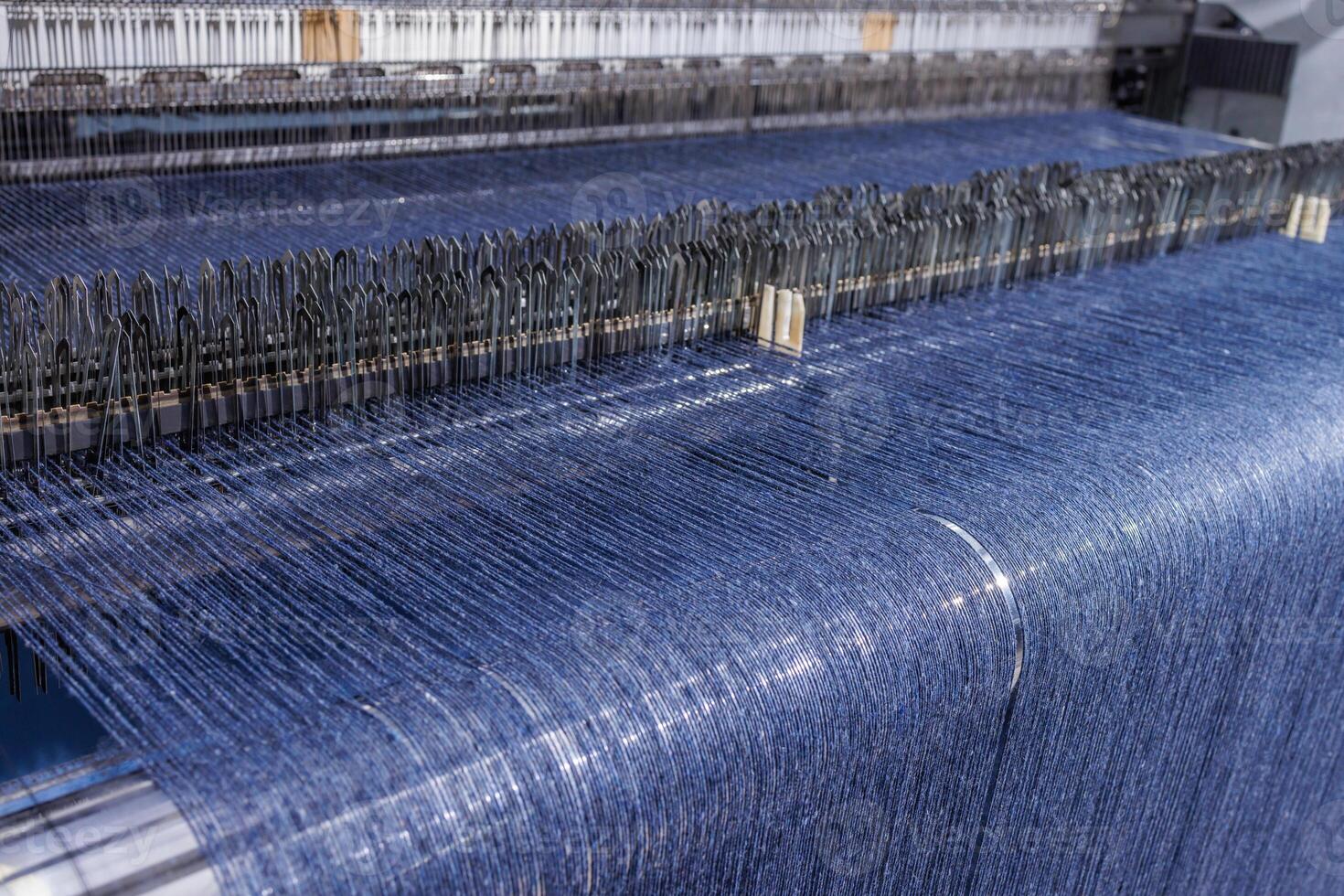 Blue threads on industrial loom weaving fabric in a modern textile manufacturing facility. photo