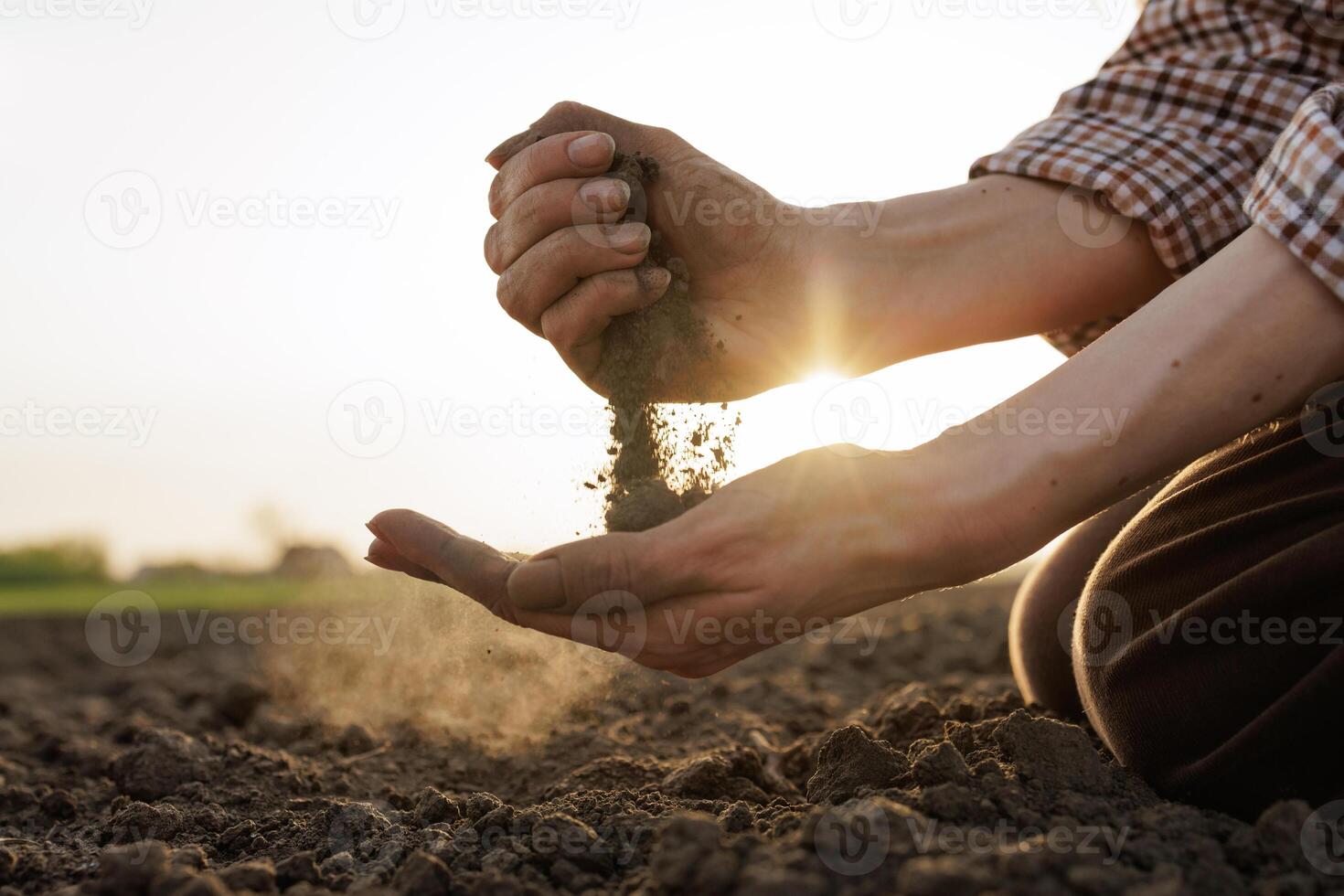Farmer's hands holding and examining soil at sunset, sustainable farming concept. photo