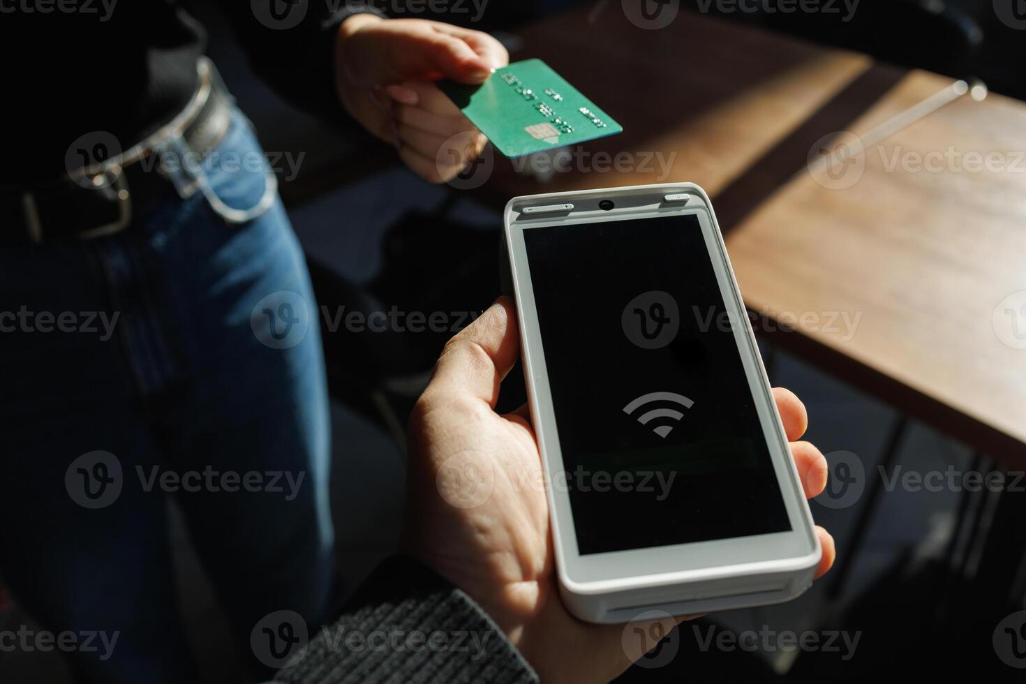 Customer making contactless payment with credit card and terminal in natural light. photo