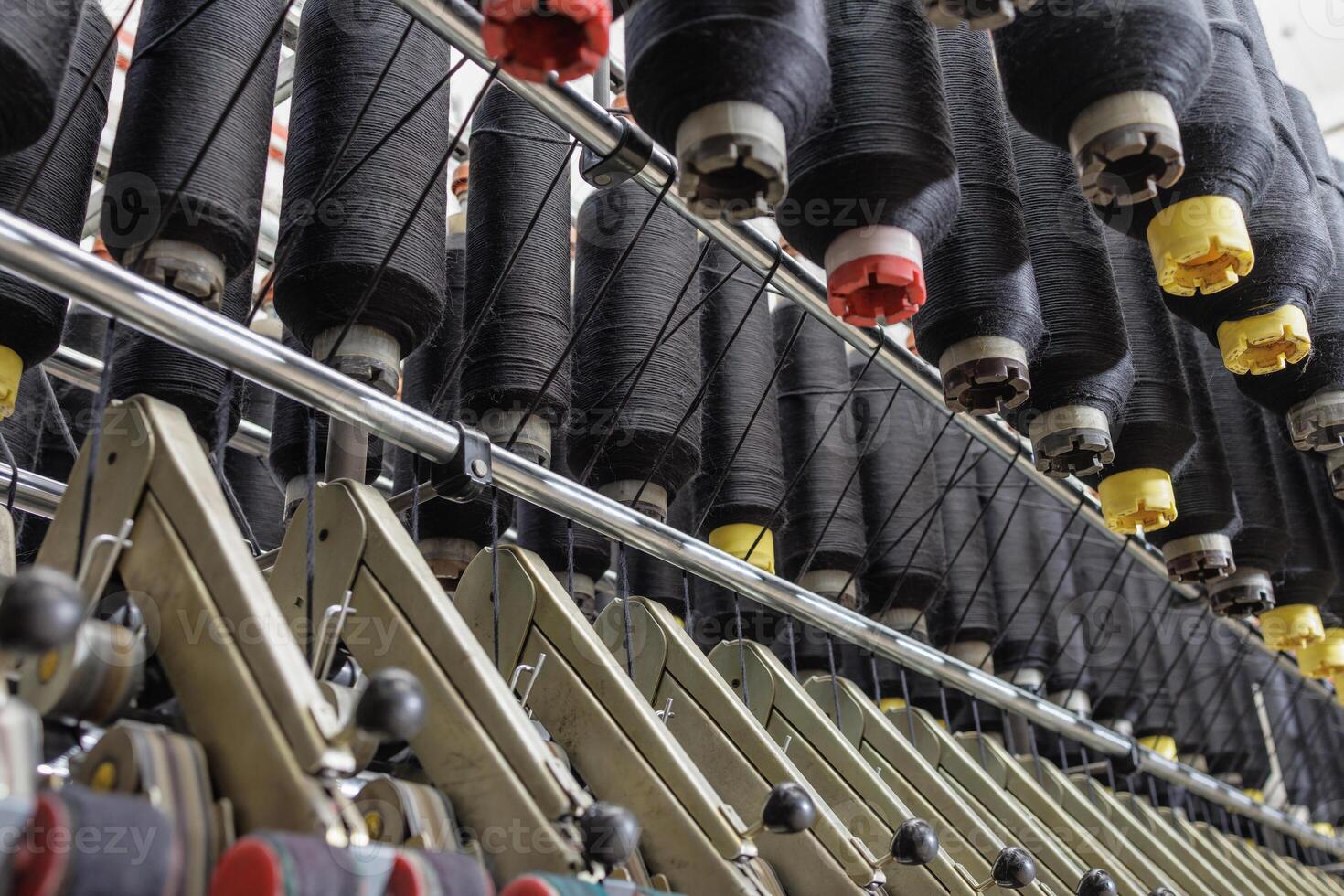 Black yarn cones on industrial textile machinery in a modern spinning or weaving factory. photo