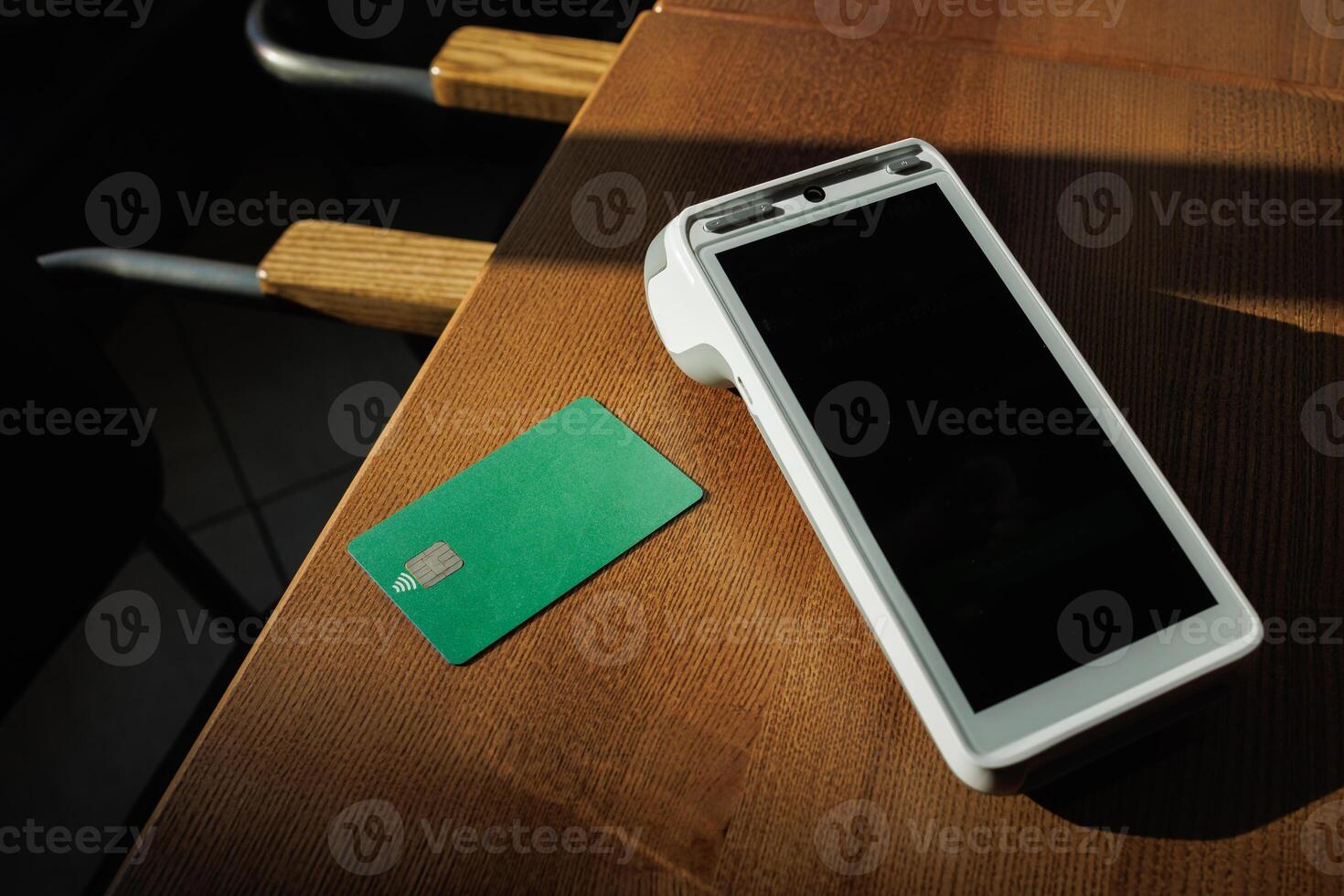 Contactless card and payment terminal on table in sunlit cafe, ready for transaction. photo