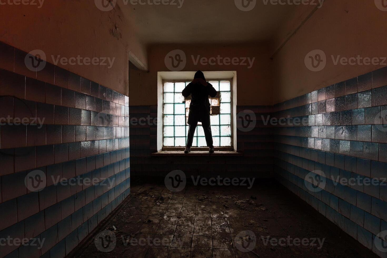 Man silhouette in abandoned building with block glass window photo