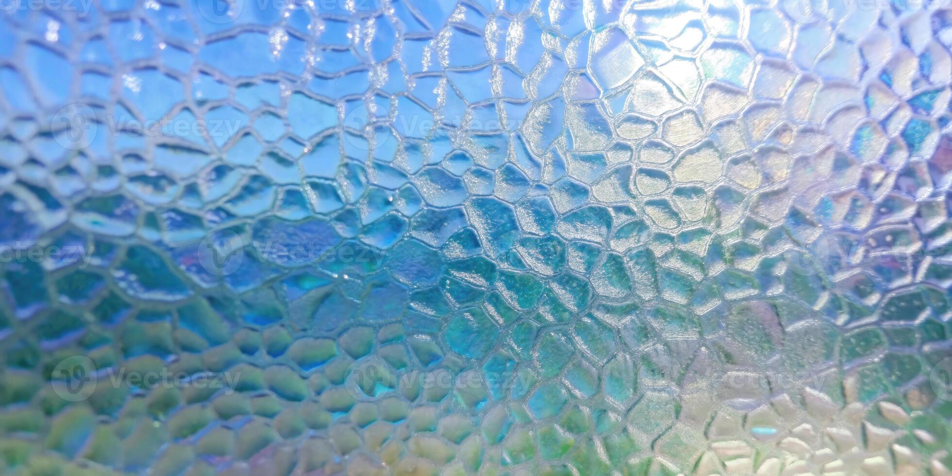 Glass surface resembling the textures of fish scales under light. photo