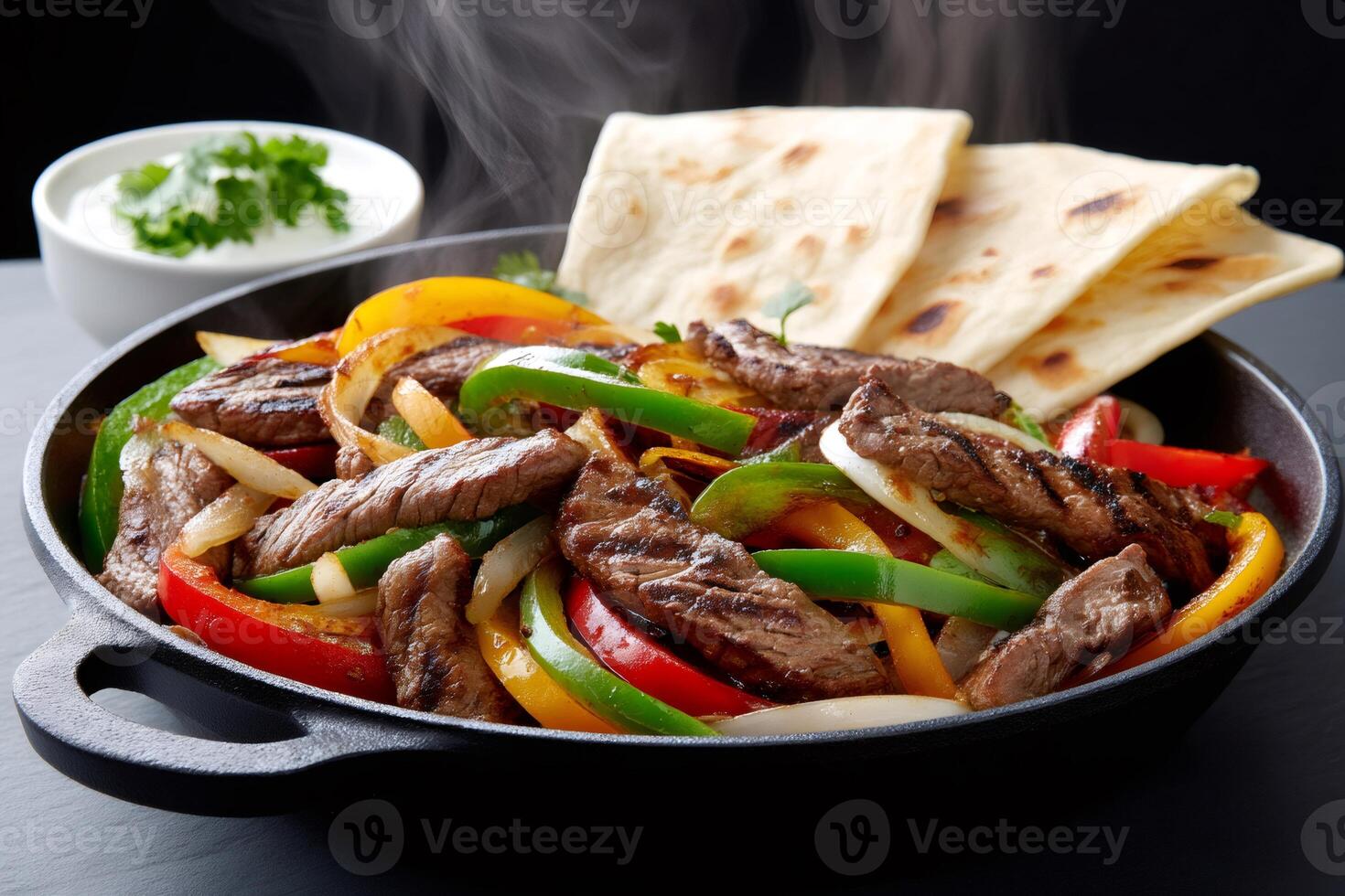 Steaming hot fajitas with tortillas and sour cream sauce photo