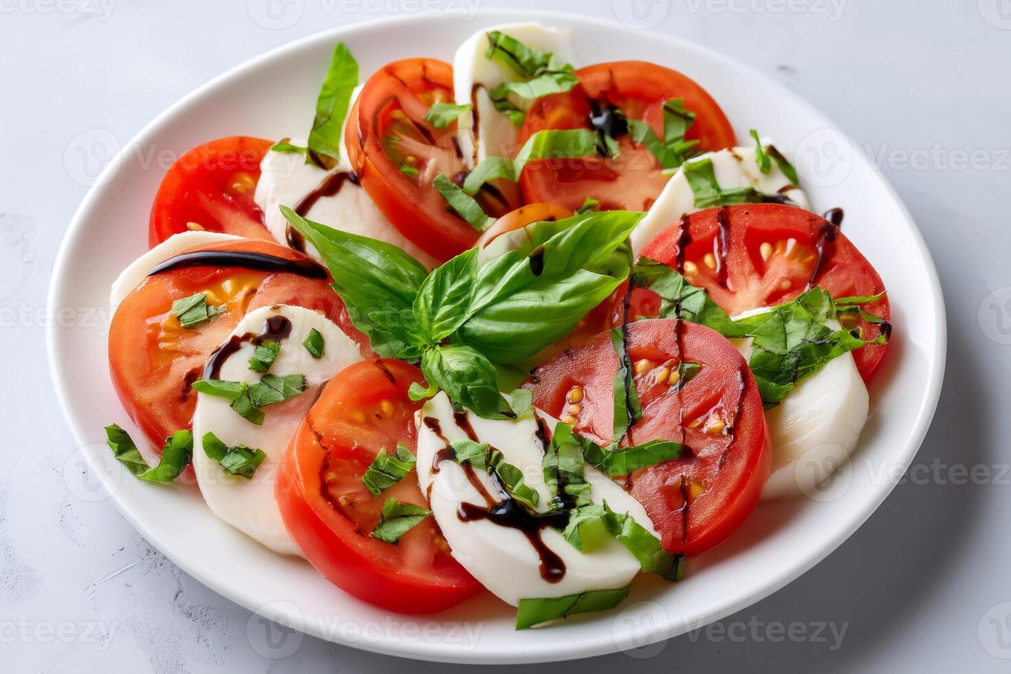 Delicious caprese salad with fresh mozzarella, tomatoes and basil seasoned with balsamic vinegar photo