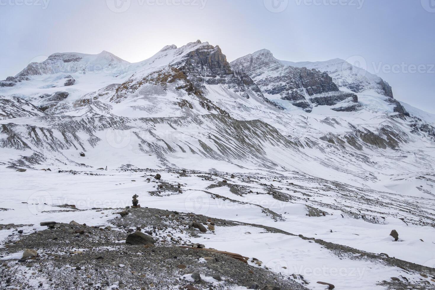 Snow-covered mountain landscape with rocky terrain under a bright sky in a remote area photo