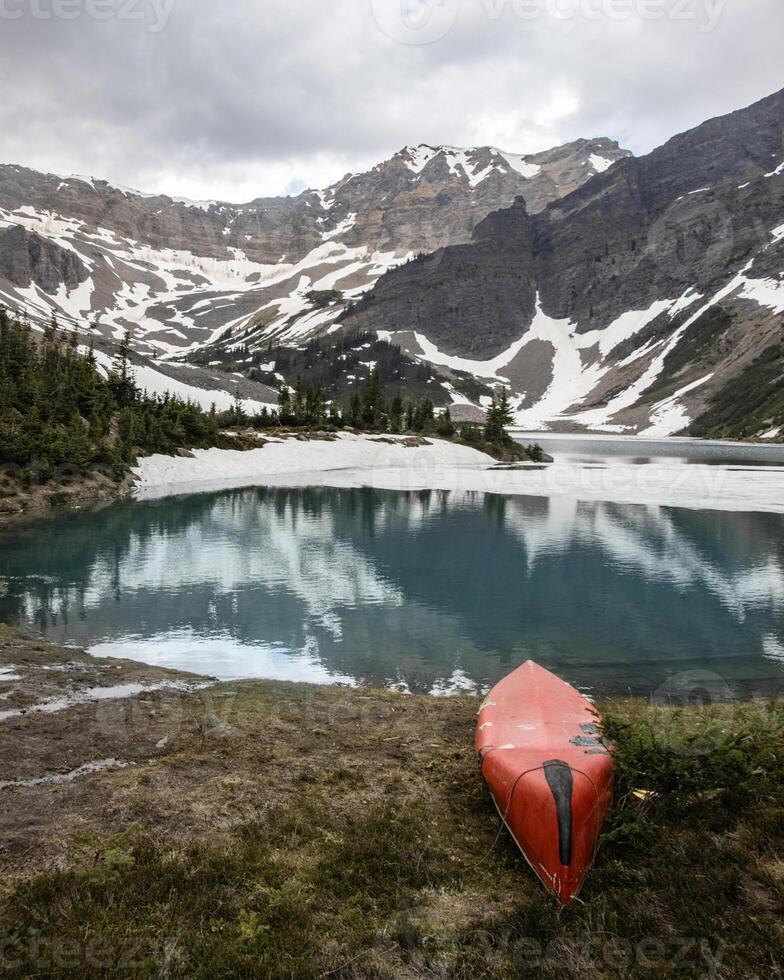 Scenic mountain lake with a red kayak resting on the shore amidst stunning natural beauty photo