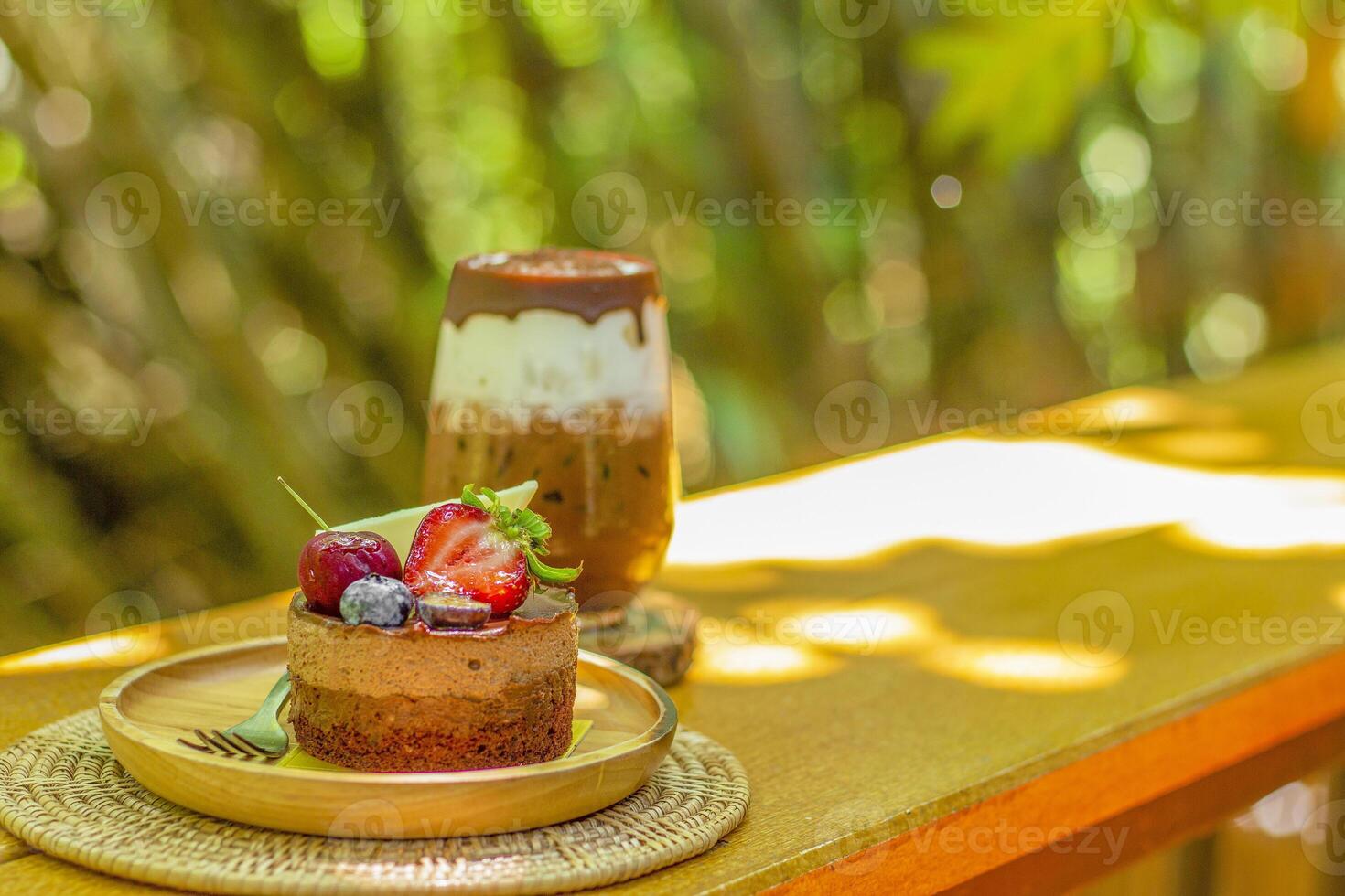 Iced chocolate - A glass of dark cocoa mixed with fresh milkand chocolate sauce on wooden table and blurred background. Summer sweet drink. photo