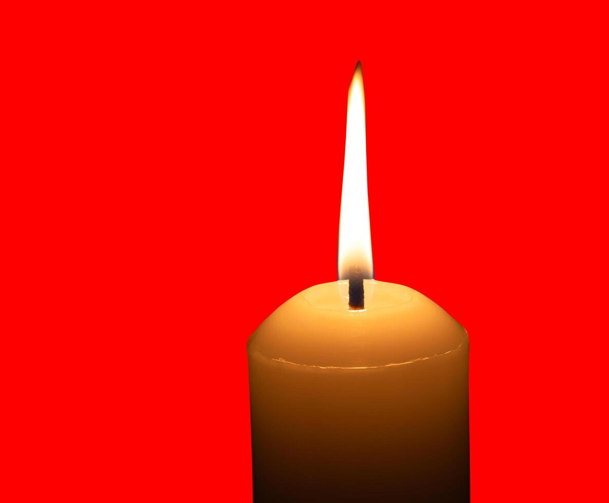 A yellow burning candle isolated on red background with clipping path photo